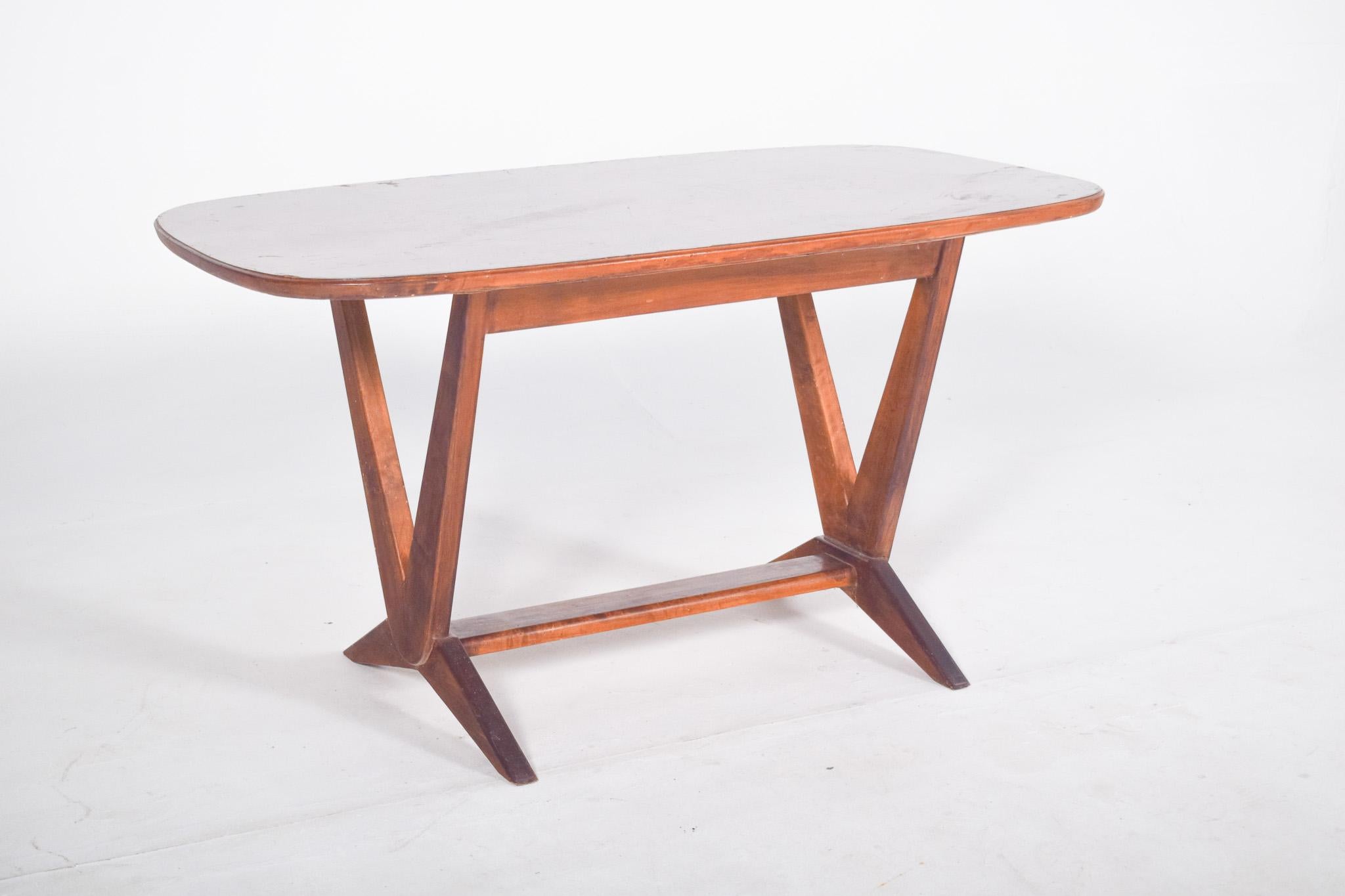 Rectangular coffee table with V-shaped legs. With rounded corners and a light colour, it has a smooth finish and gently curved edges. The top has no carvings or mouldings and is directly superimposed on the support structure. 
The support is made up