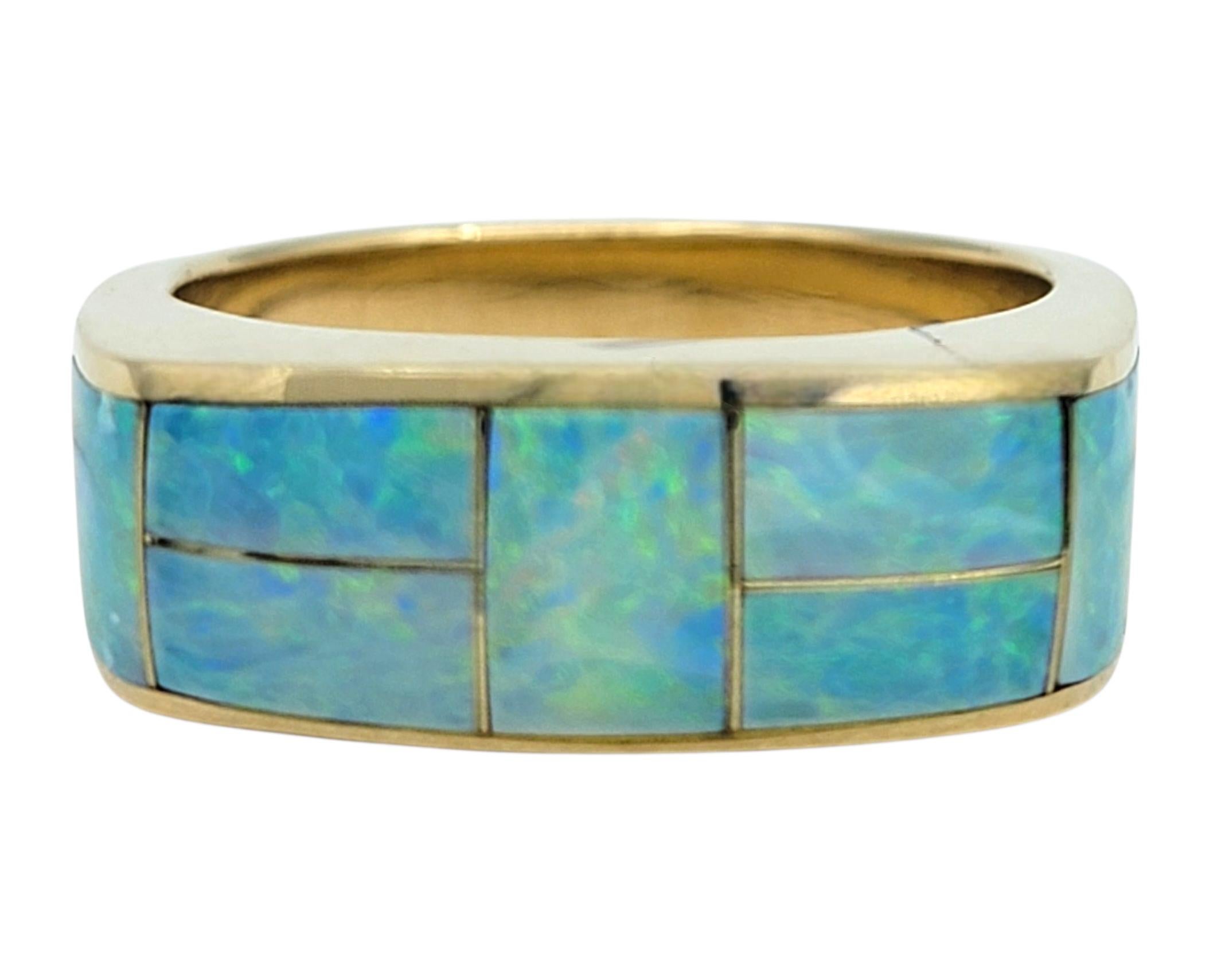 Ring Size: 7.75

This striking ring features a seamless inlay of rectangular-cut opals that wrap elegantly around the band in a modern mosaic design. Each opal displays shifting tones of blue, green, and violet, creating a vibrant interplay of color