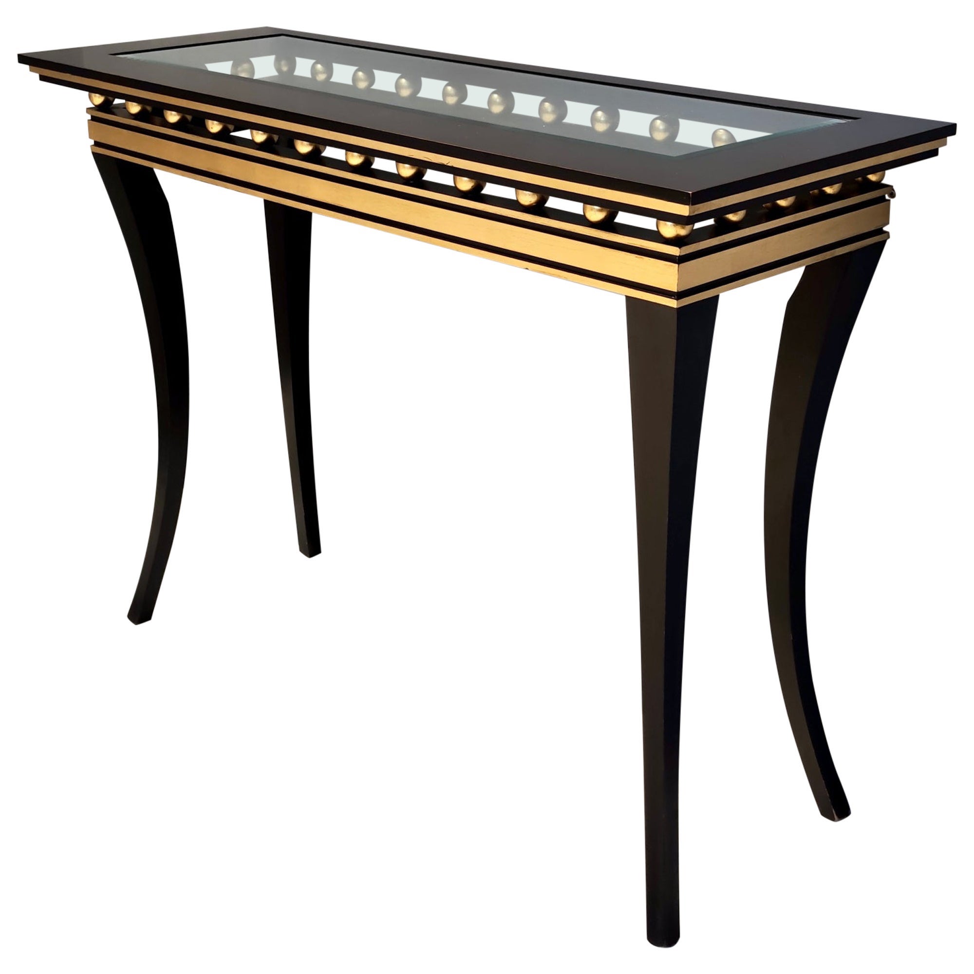 Fabricado en Italia, años 2000.
Esta consola tiene un marco de haya ebonizada con detalles lacados en dorado y una tapa rectangular de cristal biselado.
Puede mostrar ligeras huellas de uso al ser vintage, pero se puede considerar que está en