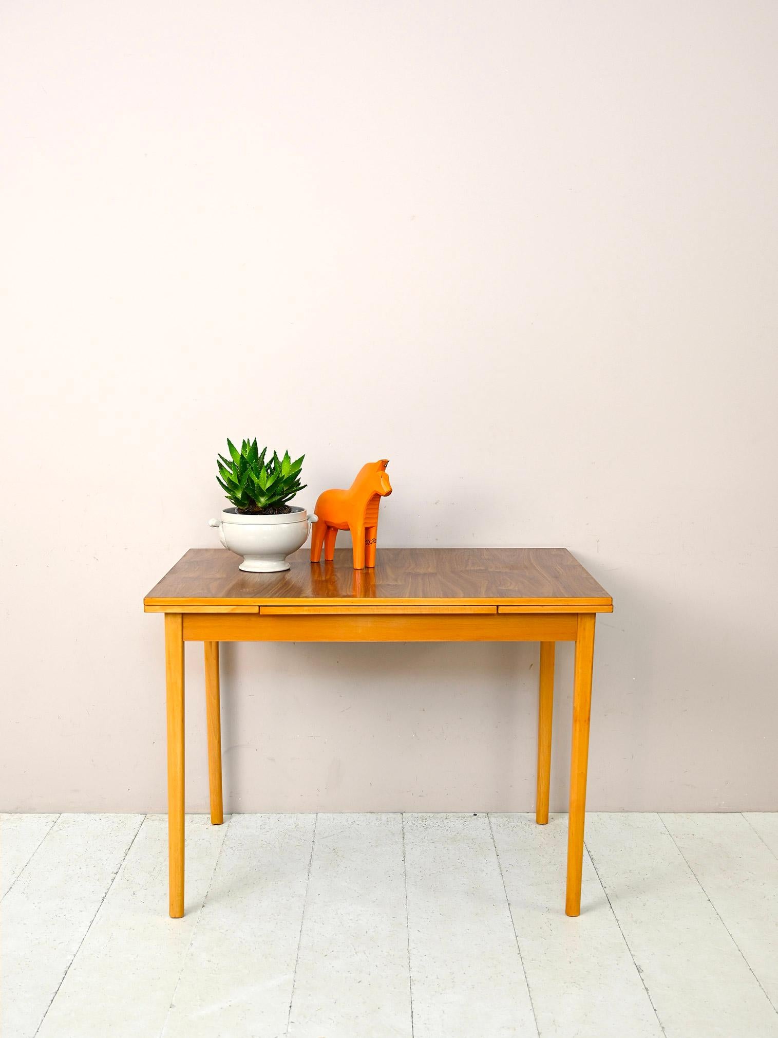 Scandinavian 1960s vintage extendable table.

This typical mid-century piece of furniture is distinguished by its faux-wood formica top that makes it very durable without sacrificing style.
Thanks to the presence of the side planks, it can be