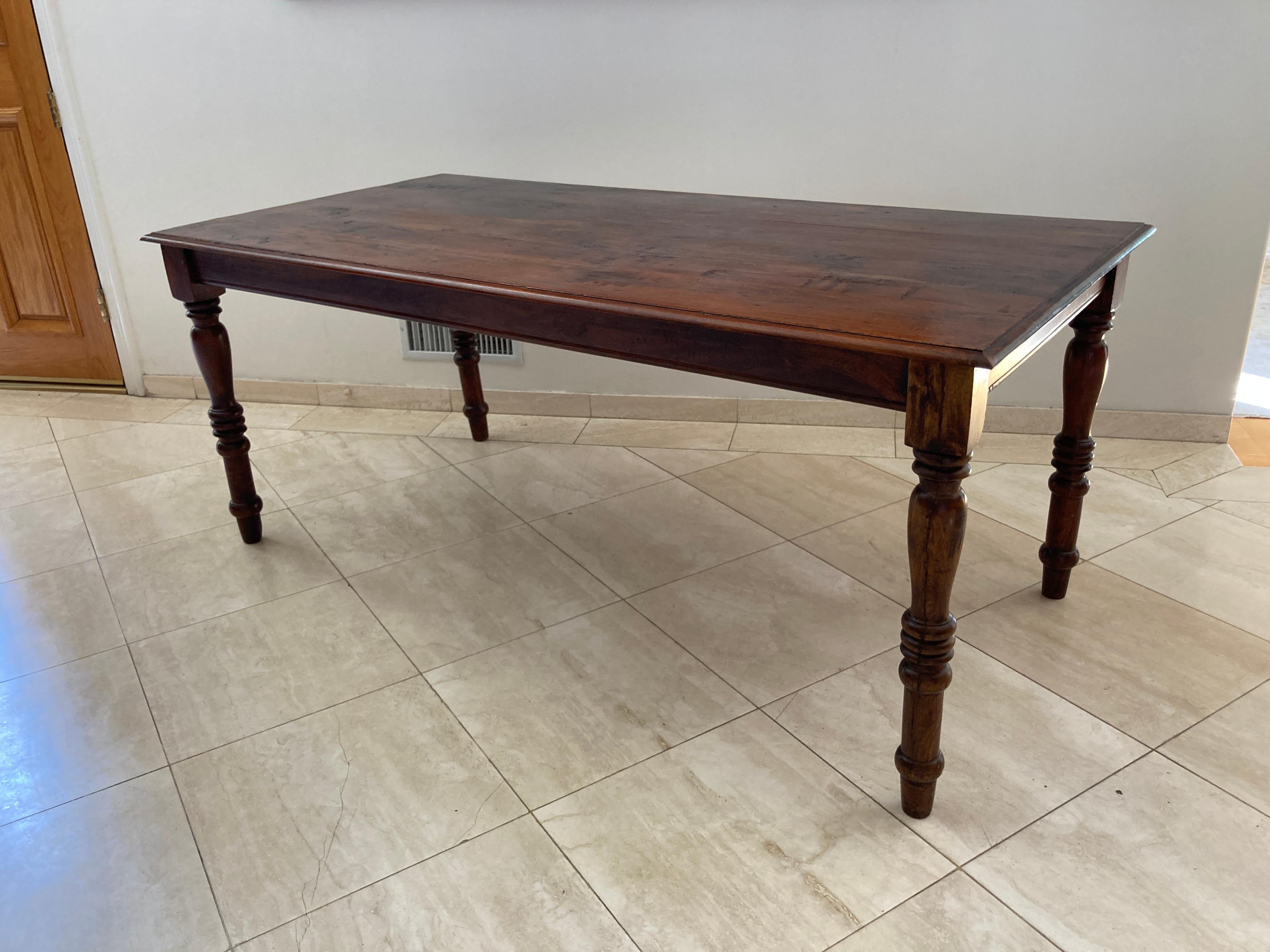 Rectangular French country rustic Provincial style dining table with distressed planked antiqued distressed stained wood top supported by turned legs ending with peg feet.
Classic European rustic stained farmhouse refectory dining table or dining