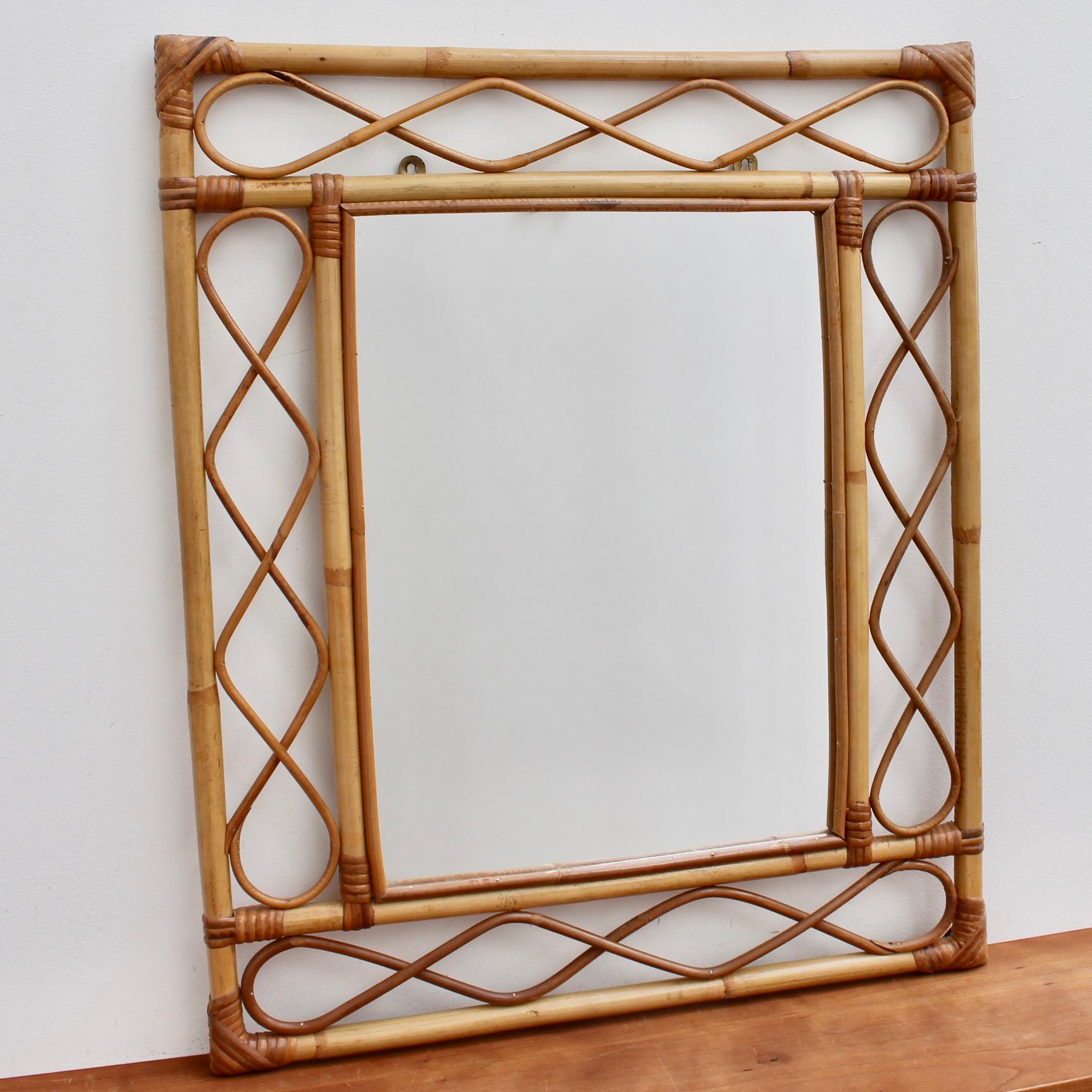 Rectangular French rattan wall mirror (circa 1960s). This is an Asian-inspired design with inner and outer frames connected by figure-eight shapes of rattan cane. The corners are lashed together and protected with rattan strands. Incredibly stylish,