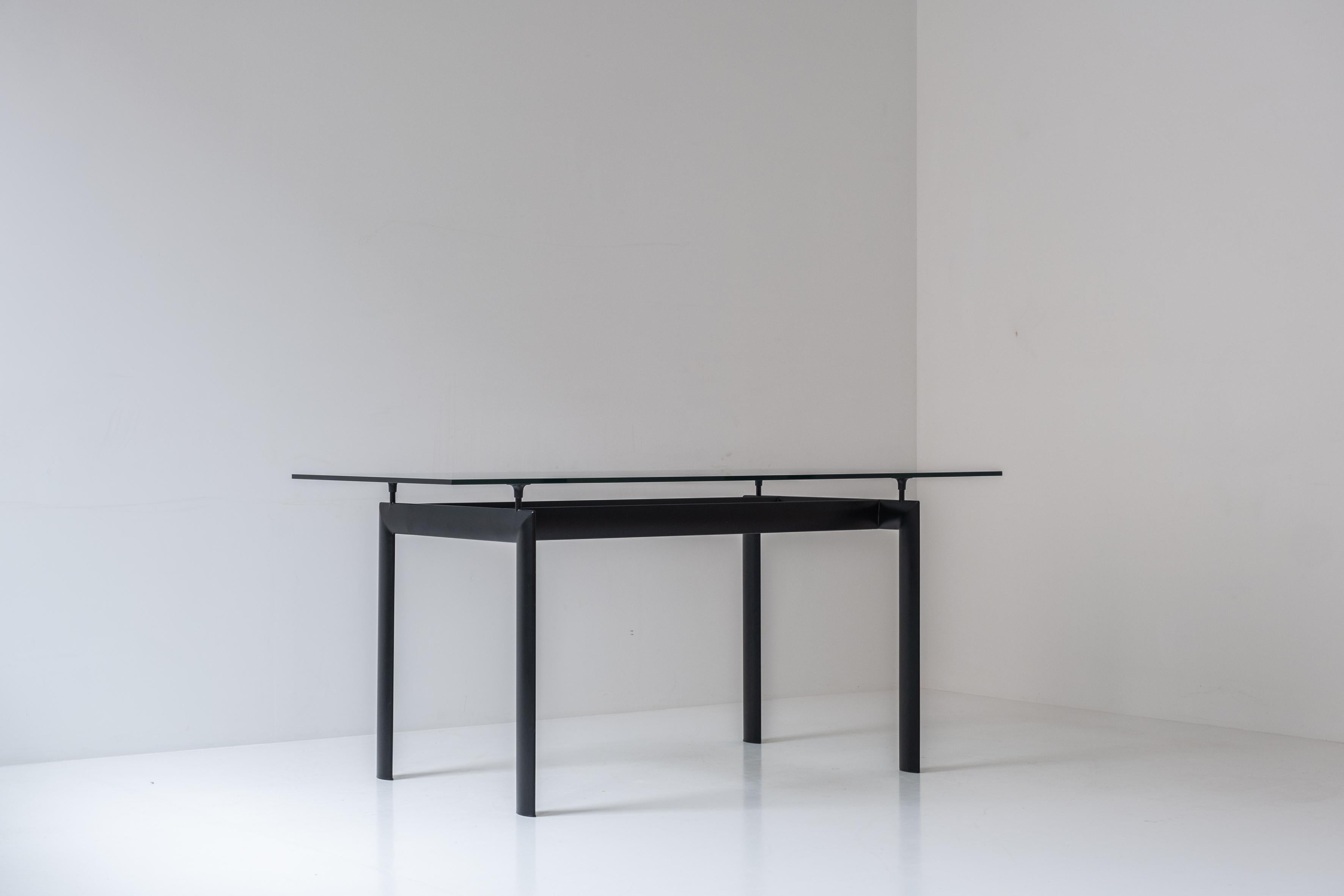 Table de salle à manger rectangulaire des années 1980. Cette table est composée d'une base en aluminium laqué noir et d'un plateau en verre. Présenté en très bon état. Clairement inspirée de la LC6 de Le Corbusier.