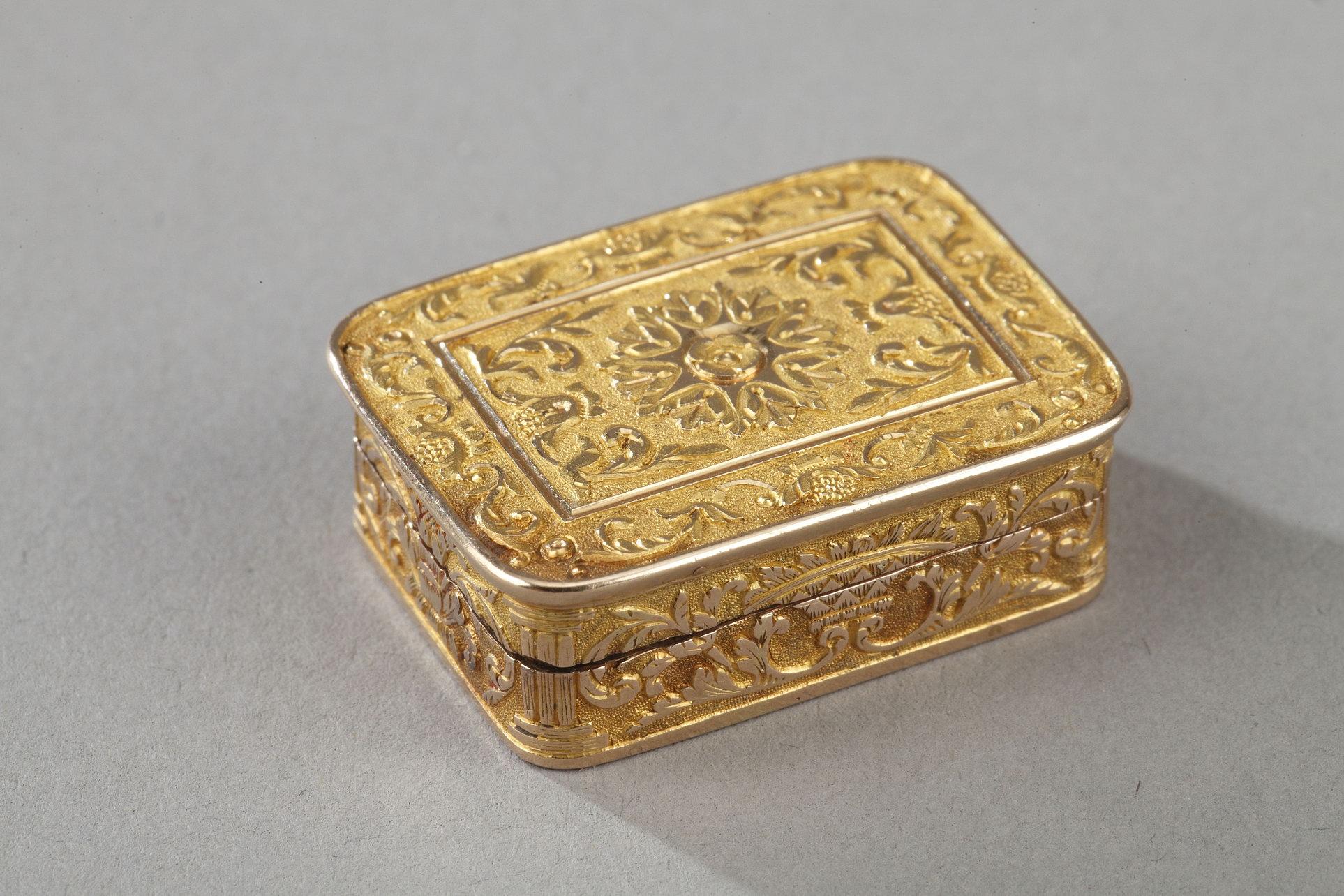 Rectangular, gold vinaigrette with a hinged lid is organized around a central pattern of stylized flower. A geometric frieze frames the composition. The bate is decorated with friezes of foliage on amati background. The background is guilloche