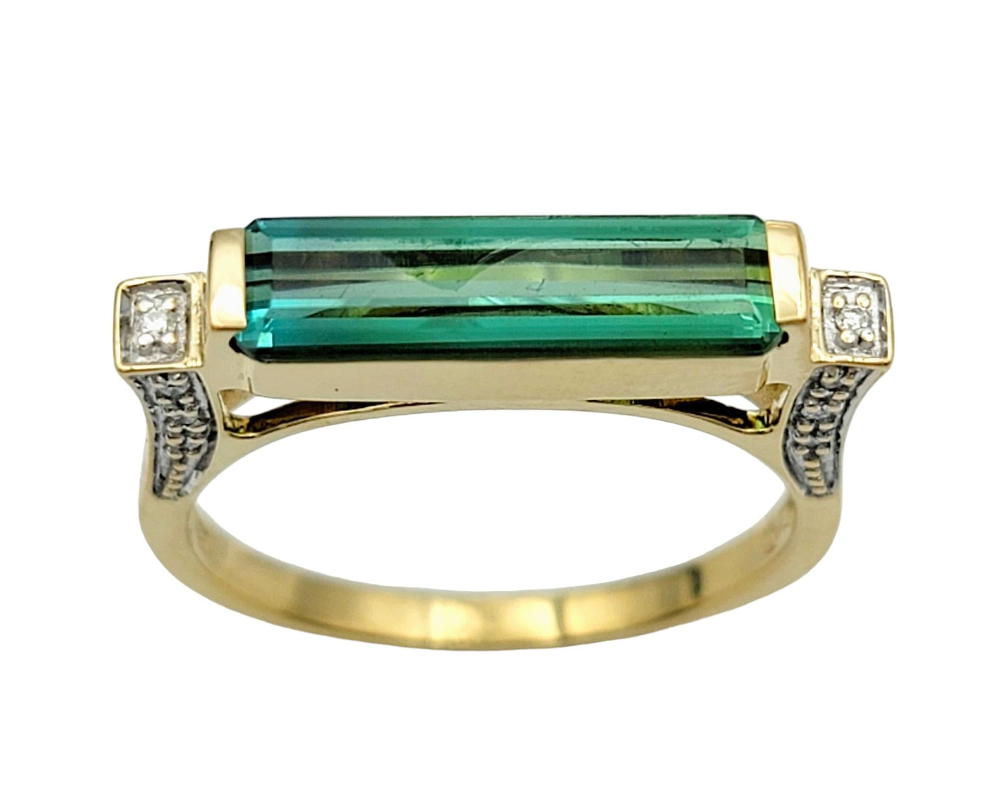 Ring Size: 6.75

This band ring exudes modern elegance with its rectangular-cut green tourmaline centerpiece, set in warm 18 karat yellow gold. Flanked on either side by round diamonds, the tourmaline captures attention with its vibrant green hue,