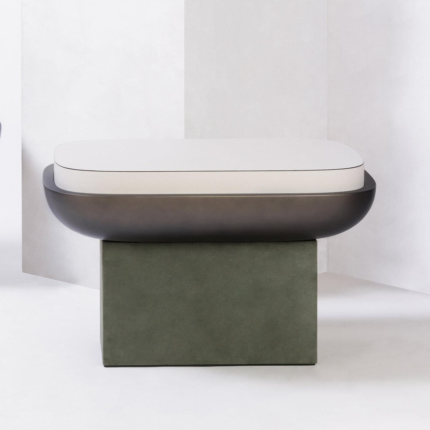 Contemporary rectangular leather stool - Olympia by Stephane Parmentier for Giobagnara.
The object presented in the image has following finish: F95 Off White Nappa Leather (top), A02 Loden Green Suede Leather (base) and Bronze-laquered Wood Seat