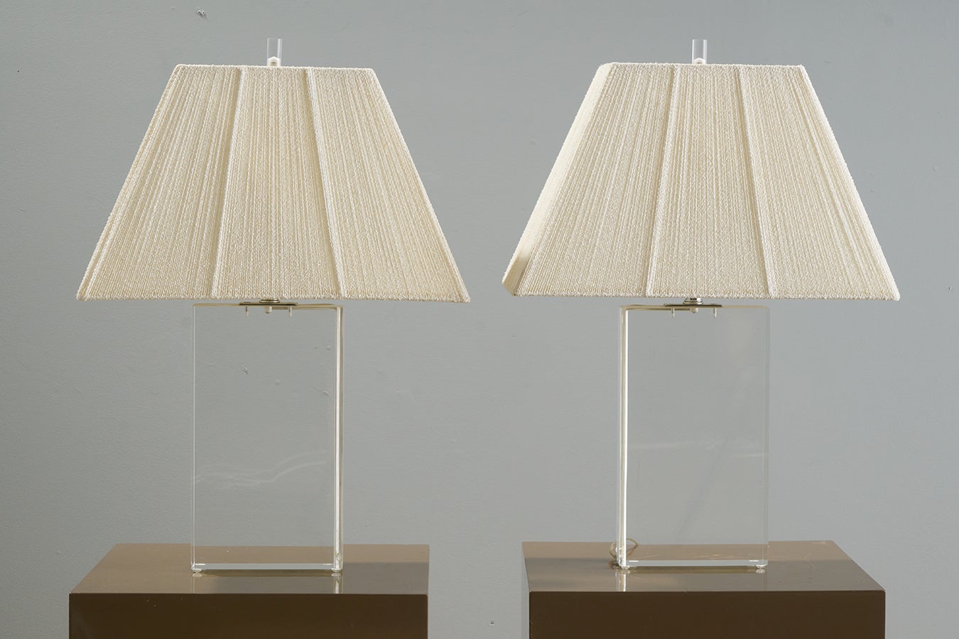 Fabulous and striking pair of vintage table lamps by renowned lamp manufacturer Lang Levin. Features an all clear acrylic (or lucite) body with a unique slot for the cord running along the side of an angled corner. Chrome hardware on top and