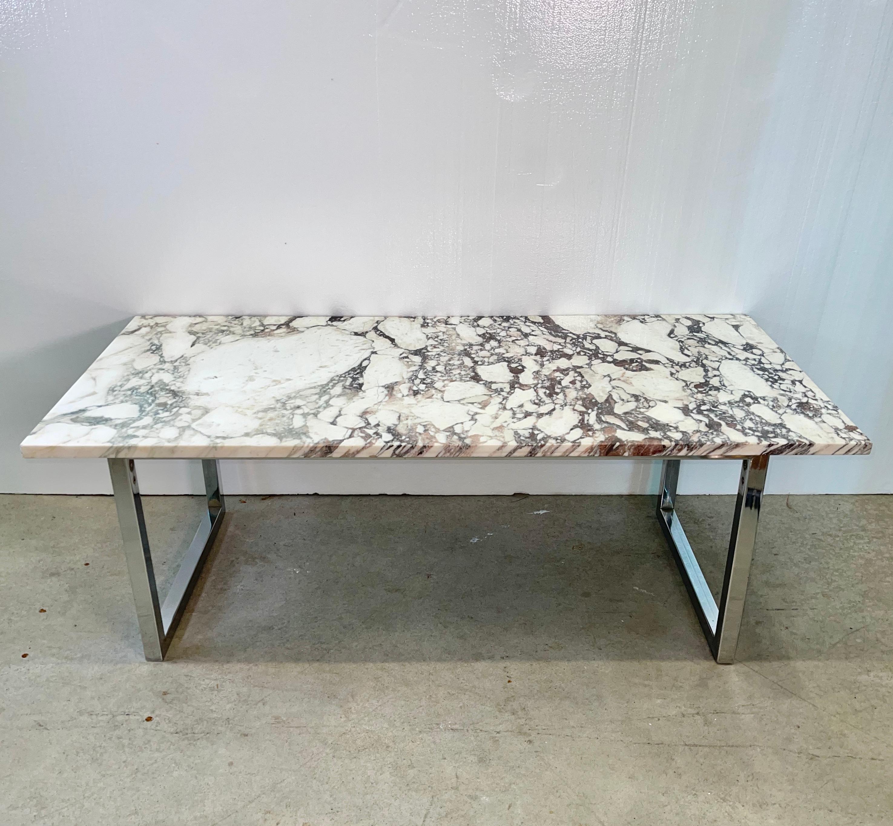 Vintage 1970s cocktail table with a one inch thick rectangular slab of polished white and black marble top on a modernist chromed square tube frame base. Simple clean lines.
Remnants of a label on the underside suggest the marble's origin is Spain