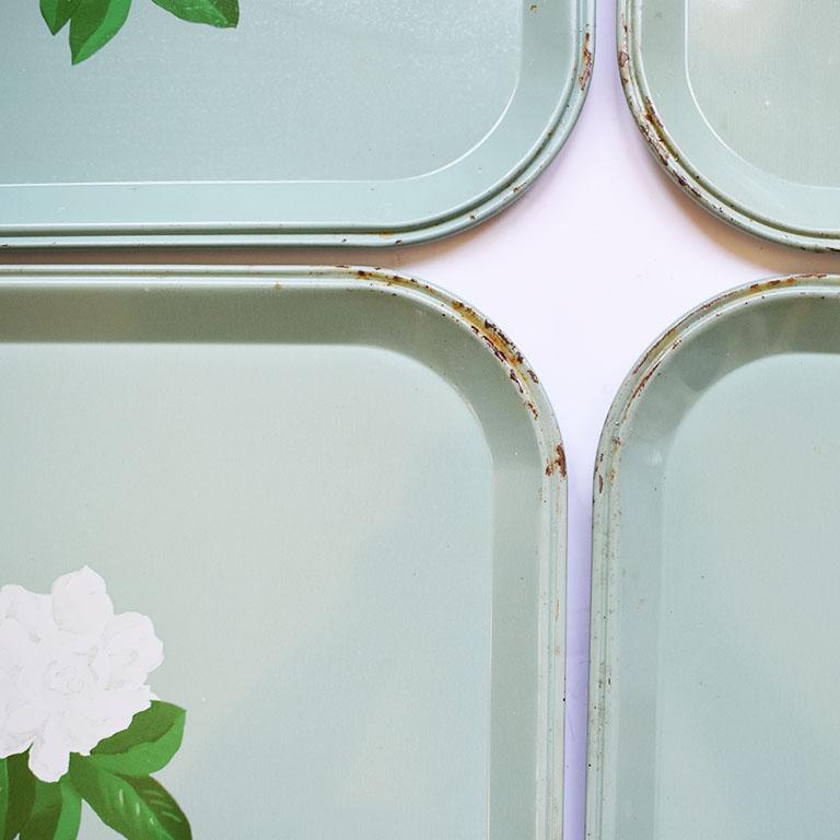 Set of six mint green snack trays. Each tray features a crisp white magnolia with green leaves painted on a mint green background. Trays are rectangular in shape with rounded corners. The bottoms is signed with “R” in red along with a stamped number