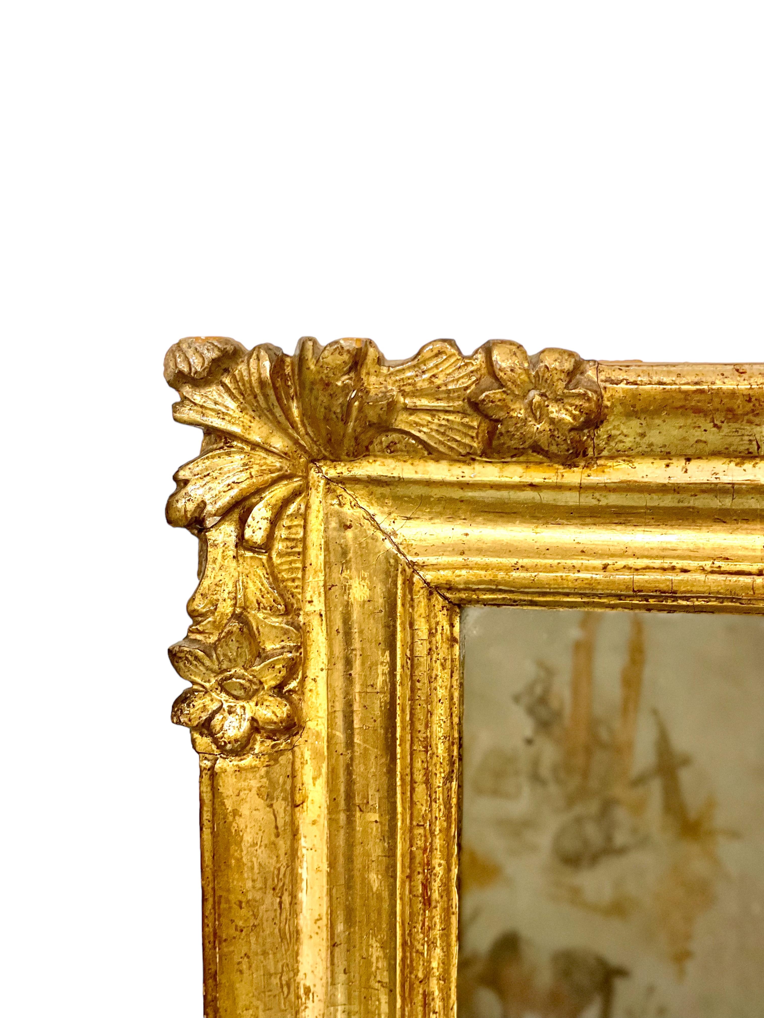 Joli petit miroir rectangulaire en bois sculpté et doré, dont les quatre coins sont ornés de sculptures de petites fleurs et de gerbes d'acanthe. Datant du XIXe siècle, ce charmant miroir a conservé sa plaque de verre d'origine et porte une