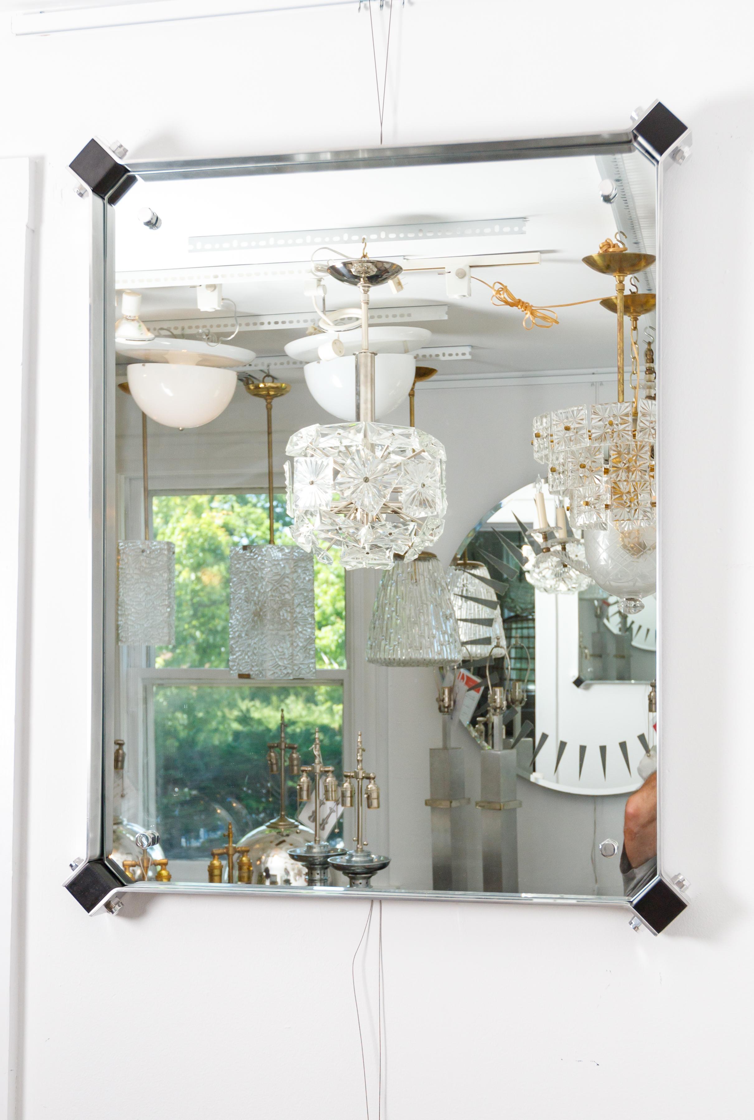 Miroir rectangulaire avec entourage en acier inoxydable avec détails d'angle noirs.
