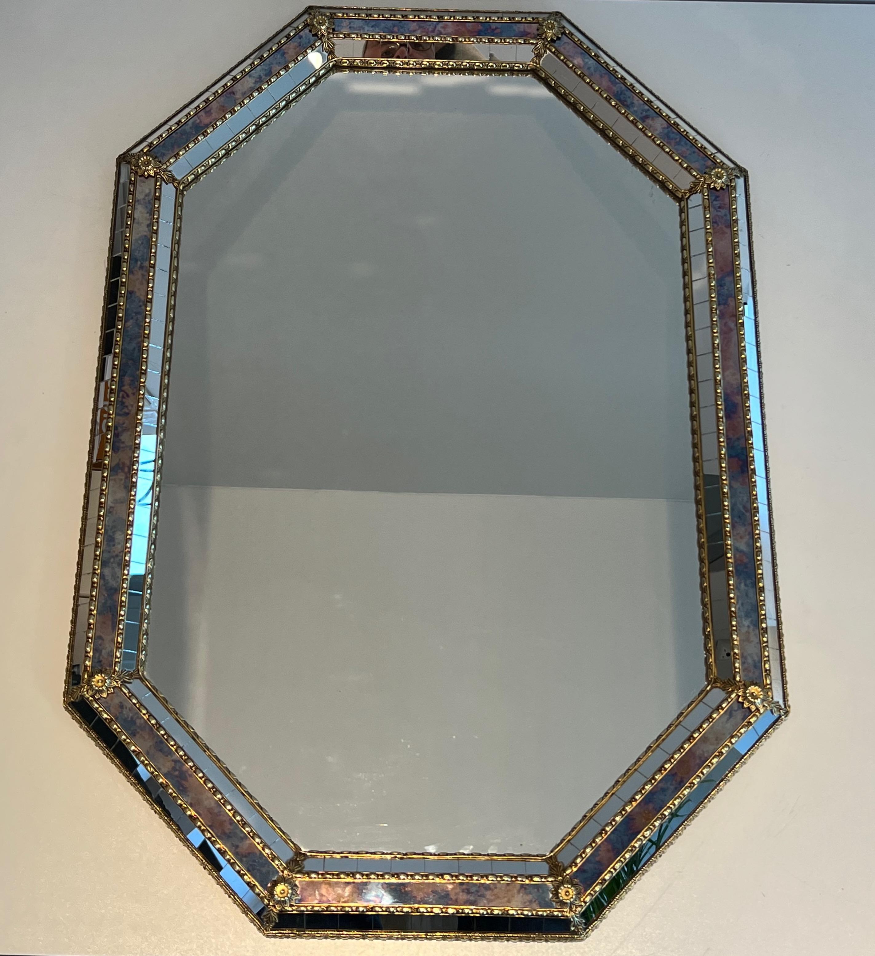 This octogonal mirror is made of multi-facets mirrors with brass garlands. This is a French work. Circa 1970