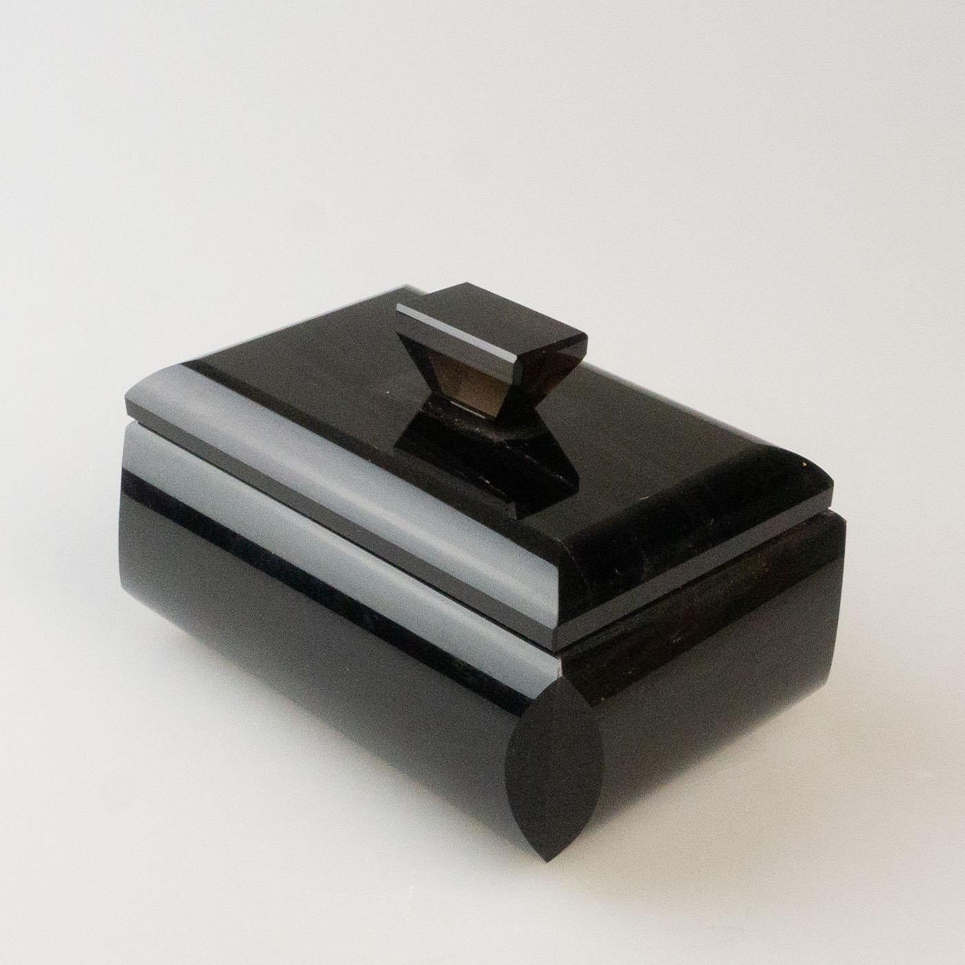Boîte rectangulaire en obsidienne noire massive composée d'une base et d'un couvercle avec un bouton pour faciliter l'ouverture. L'intérieur de cette boîte à bijoux géométrique est doublé de velours taupe doux pour ranger vos bijoux. L'obsidienne