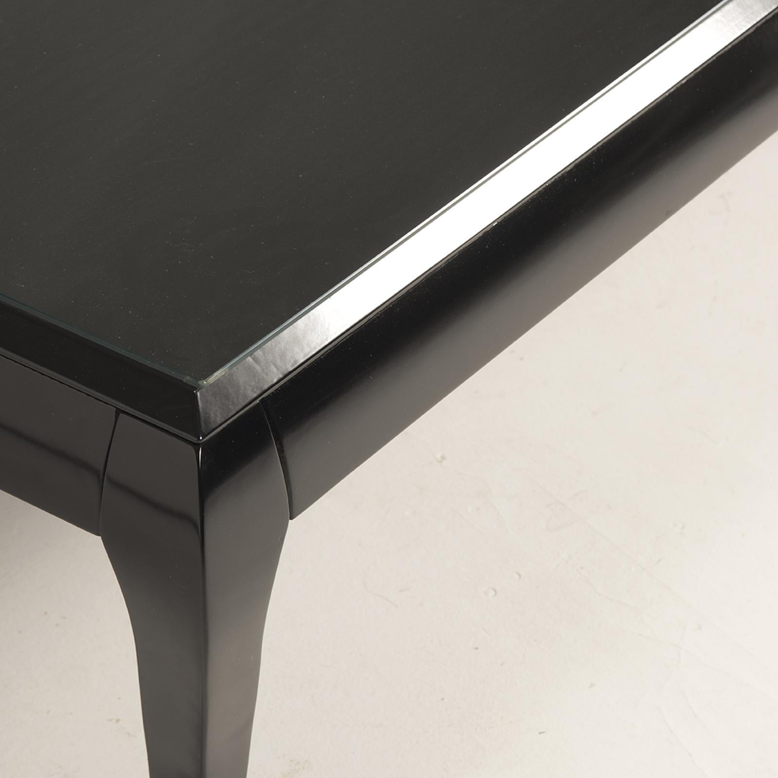 This exquisite coffee table is expertly crafted from solid wood, pairing a rectangular top with elegantly tapered legs. Offering a subtle fusion of modern and traditional styling, its understated design is distinguished by a sleek black lacquered