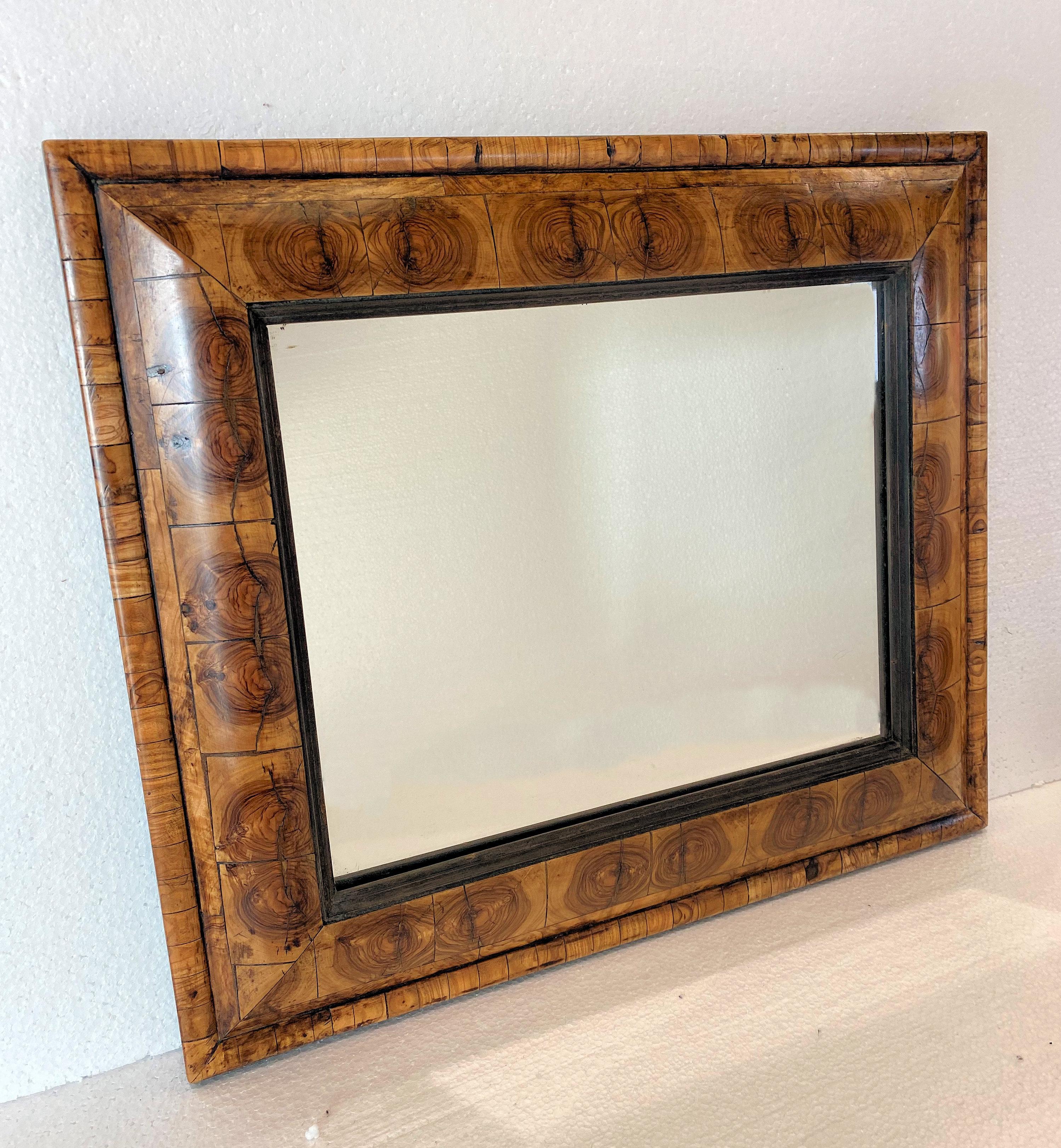 This lovely 20th century veneered cushion mirror is styled in the 17th Century design. It is rectangular in shape and features a lovely veneer design within the border. It measures 21 inches by 17.3/4 inches with a depth of 2 inches. This mirror