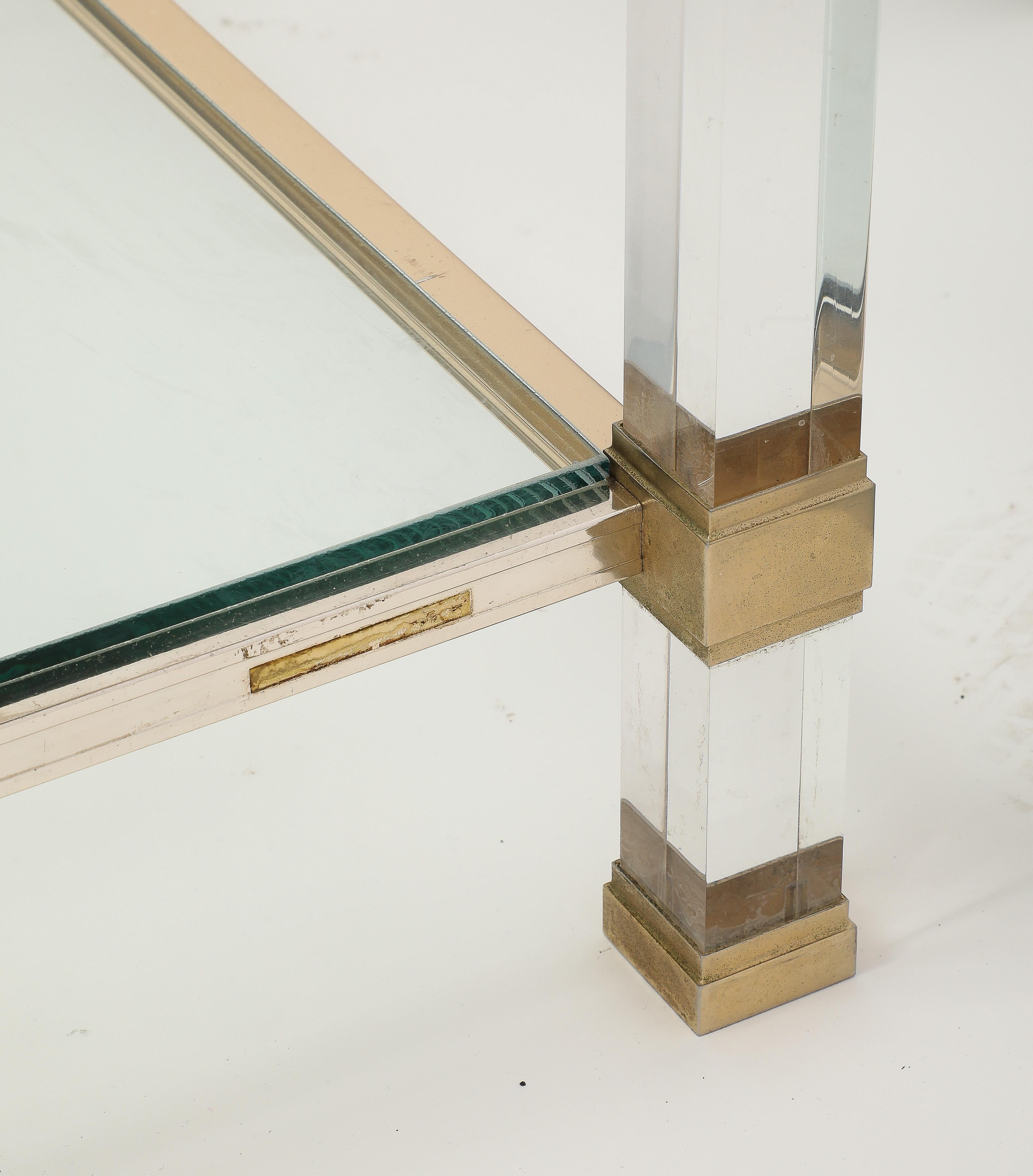 The elegance of Pierre Vandel's Coffee tables. In the 70's and 80's his collection of tables were very popular. 
This one has lucite legs with sides with brass and silver tones. It has the plaque with the signature. The height is taller than the