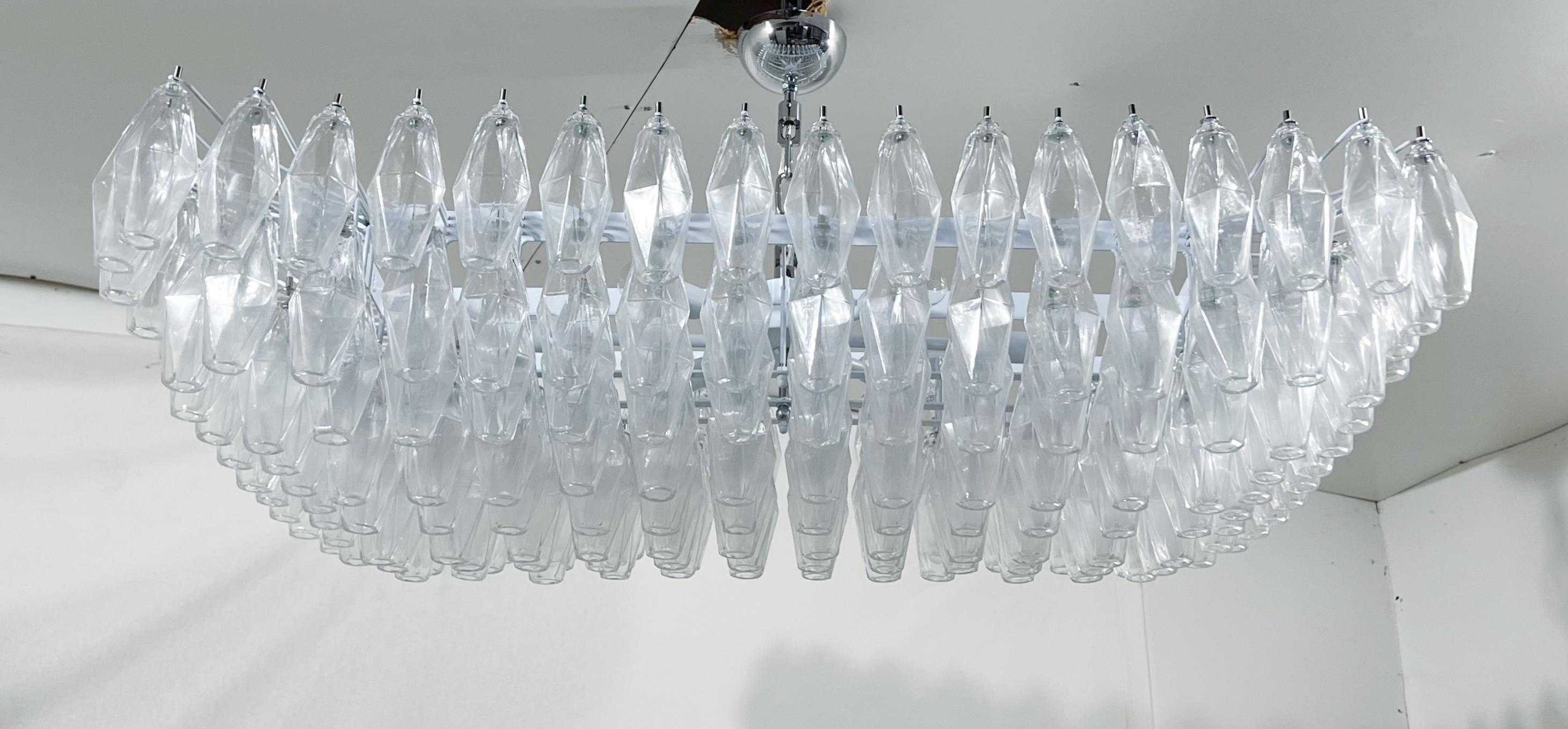 Lustre italien de forme rectangulaire avec des verres de Murano transparents en forme de polyèdres / polyédriques montés sur une structure en métal blanc avec des ferrures chromées / Fabriqué en Italie.
Mesures : Longueur : 44 pouces, largeur 26