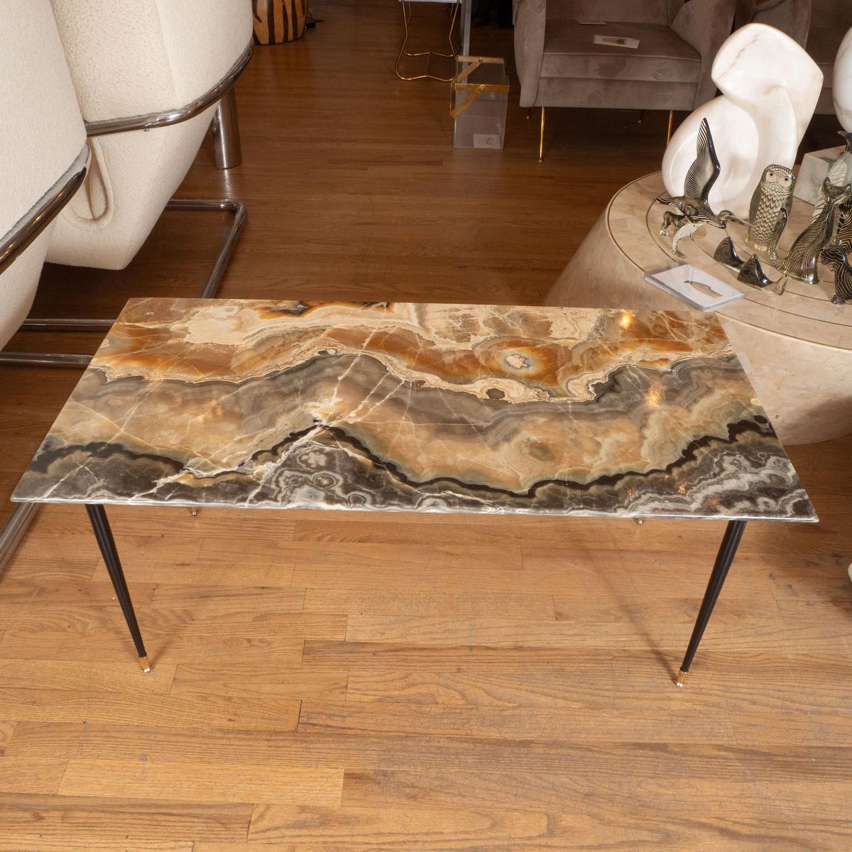 Rectangular coffee table with black metal legs and brass feet.