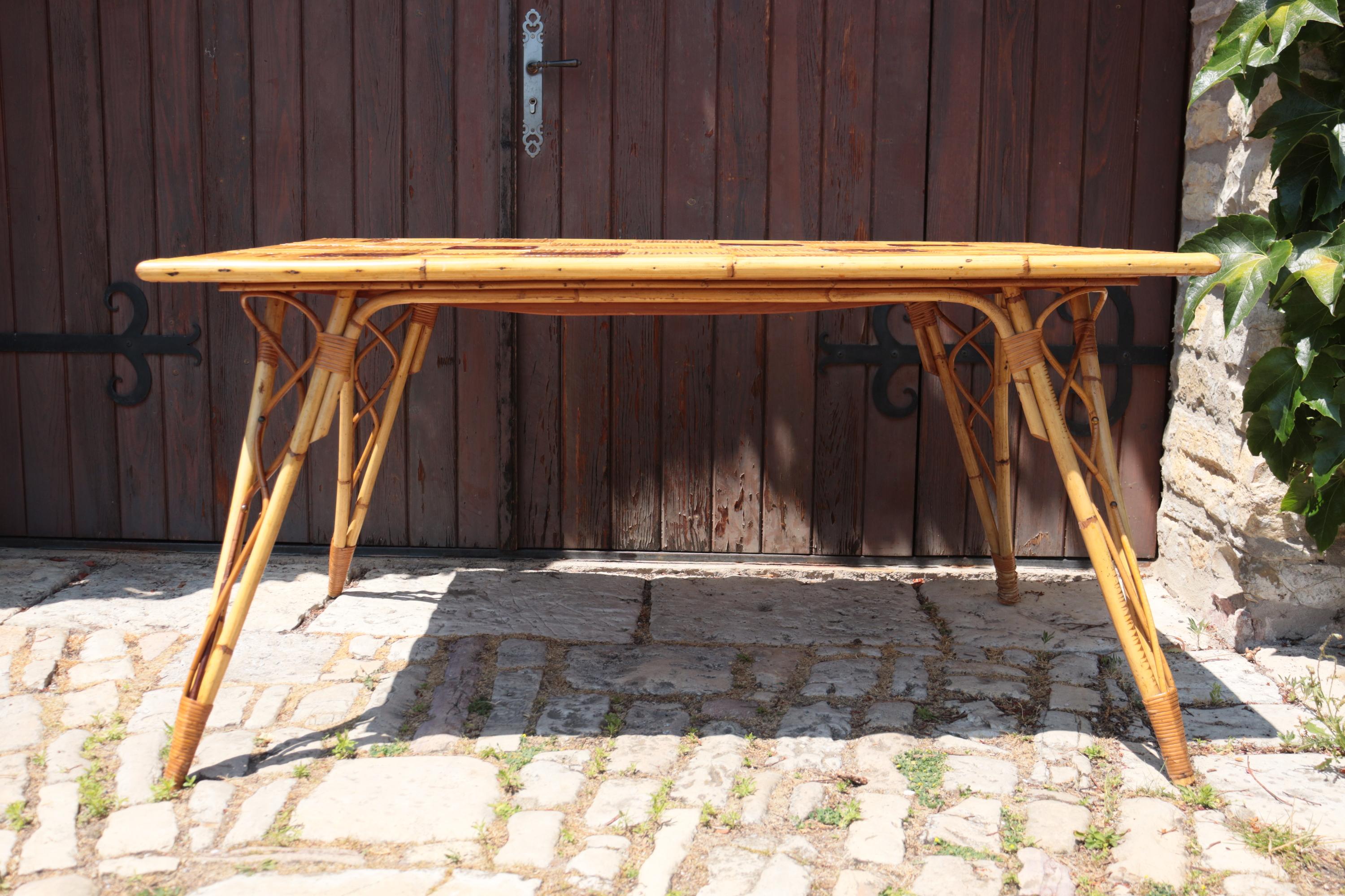 Charming rectangular table with a natural rattan structure, attributed to Adrien Audoux and Frida Minnet, iconic French designers of the 1950s, renowned for their craftsmanship and innovative use of warm, raw materials. The top is made of an elegant