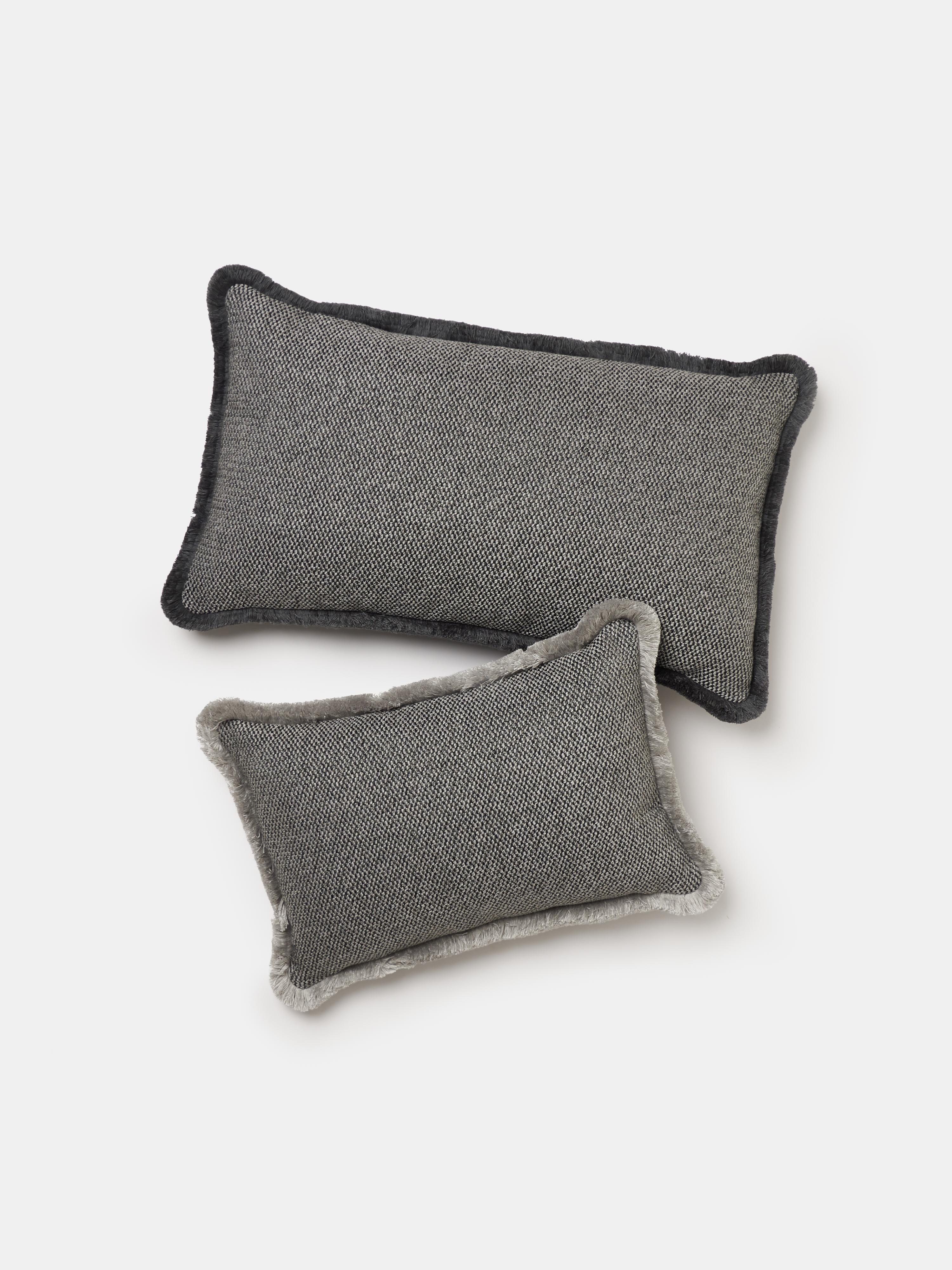 Cuscino rettangolare con frange della linea SERENO di Villa Como, realizzato a mano a Como con tessuti italiani di alta qualità. La superficie è caratterizzata da una trama ricca e strutturata in una tonalità grigio antracite, arricchita da una