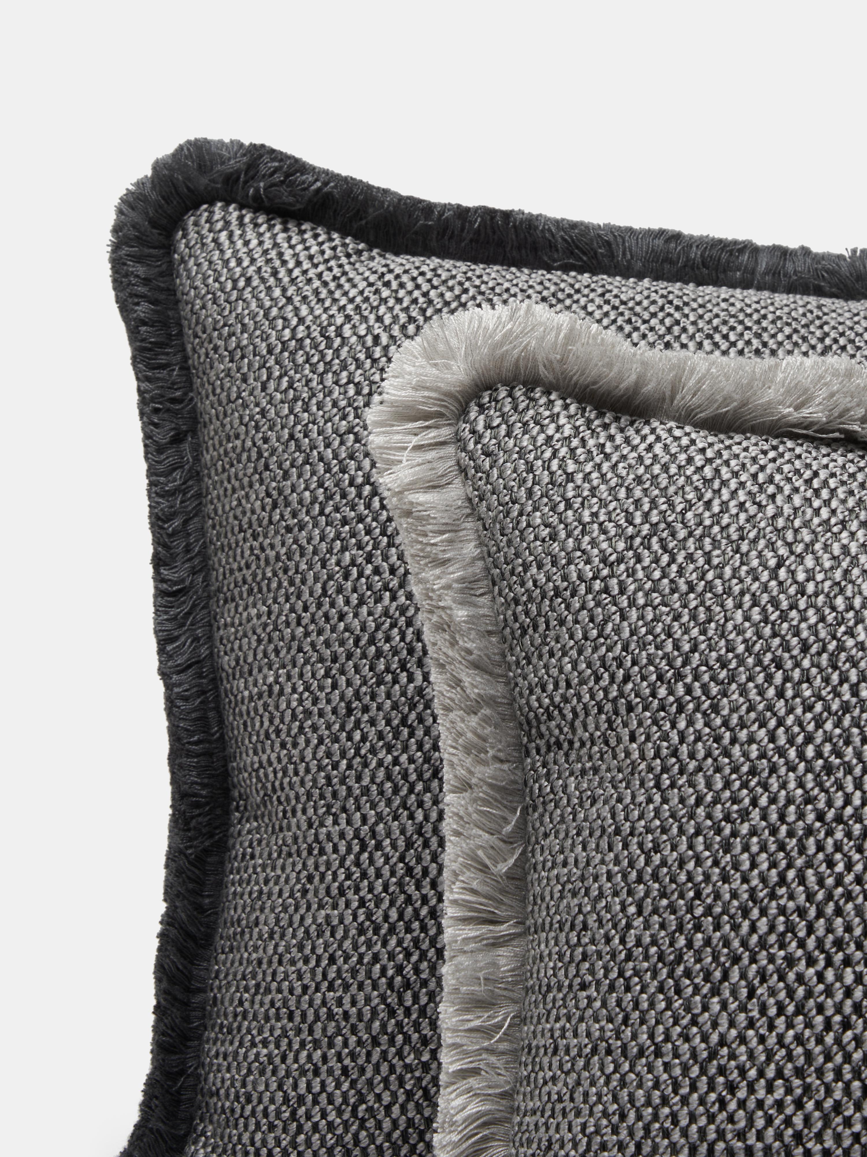 Cuscino rettangolare con frange della linea SERENO di Villa Como, realizzato a mano a Como con tessuti italiani di alta qualità. La superficie presenta una trama ricca e strutturata in grigio antracite, arricchita da una frangia perimetrale grigia