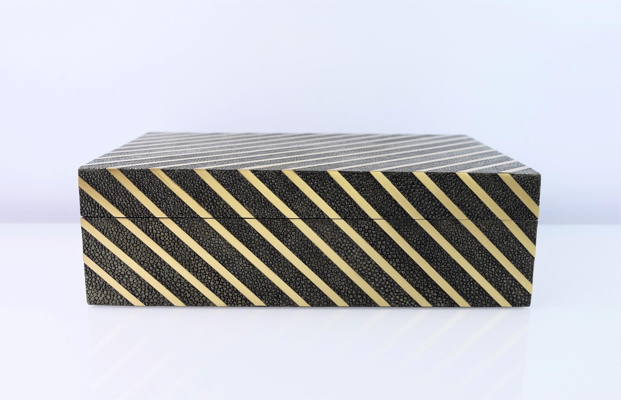 Diese moderne Box von Ginger Brown ist handgefertigt und mit Chagrin und Messingstreifen verziert.

Die Box ist mit einem Scharnier versehen und innen mit einem hochwertigen schwarzen Microsuede ausgekleidet.

Die Farbe des Zottelgrüns ist ein