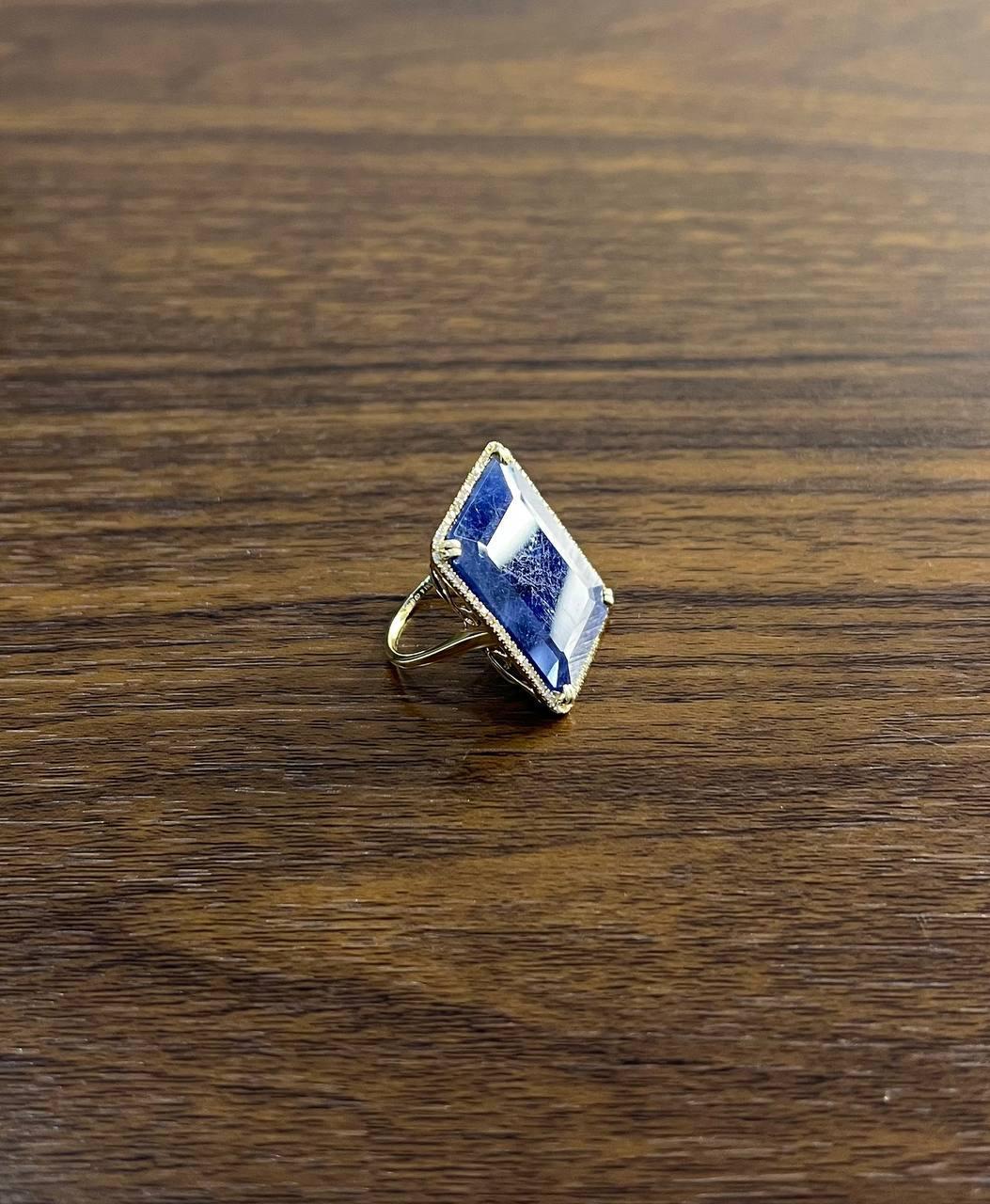 Cette bague remarquable est finement travaillée en or 14k. La pièce maîtresse est un grand saphir bleu rectangulaire.  Le cadre est orné d'une délicate bordure de diamants étincelants (0,29ct) en or jaune 14K. 25 x 20 MM Saphir bleu.