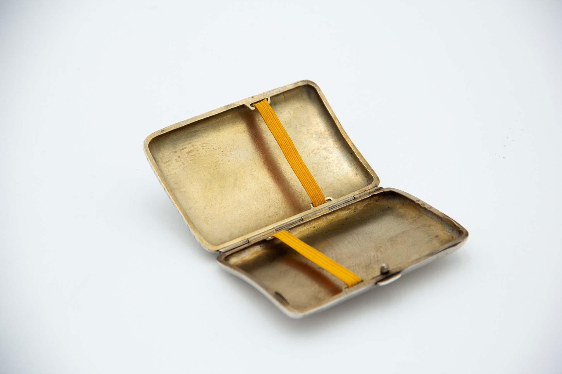 Descrizione: Portasigarette rettangolare in argento con motivi floreali incisi, forma curva, interno dorato e coperchio a molla. Metallo: Argento. Origine: Tedesca. Marchio: Sconosciuto. Peso: 59,11 grammi. Dimensioni: 8,5 cmx1,4 cm. Contenuto: