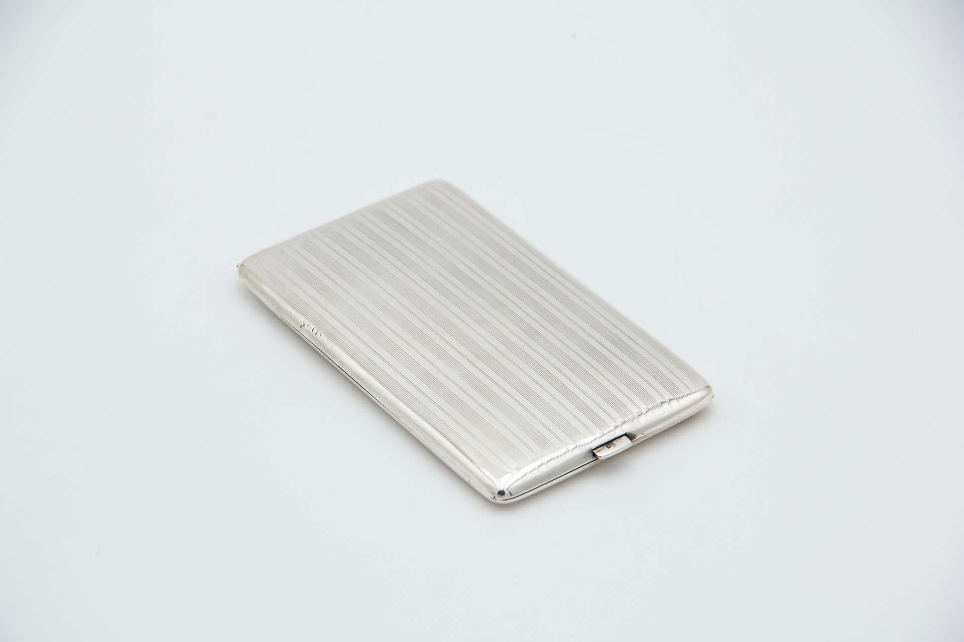 Description: Rectangular silver cigarette case with longitudinal bands on the hinged lid. Metal: Silver. Origin: Portuguese. Brand: javali II Title. Weight: 151.38 grams. Dimensions: 14cmx1.2cm. Content: 833/1000. Assay Mark: Yes, between 1887 and