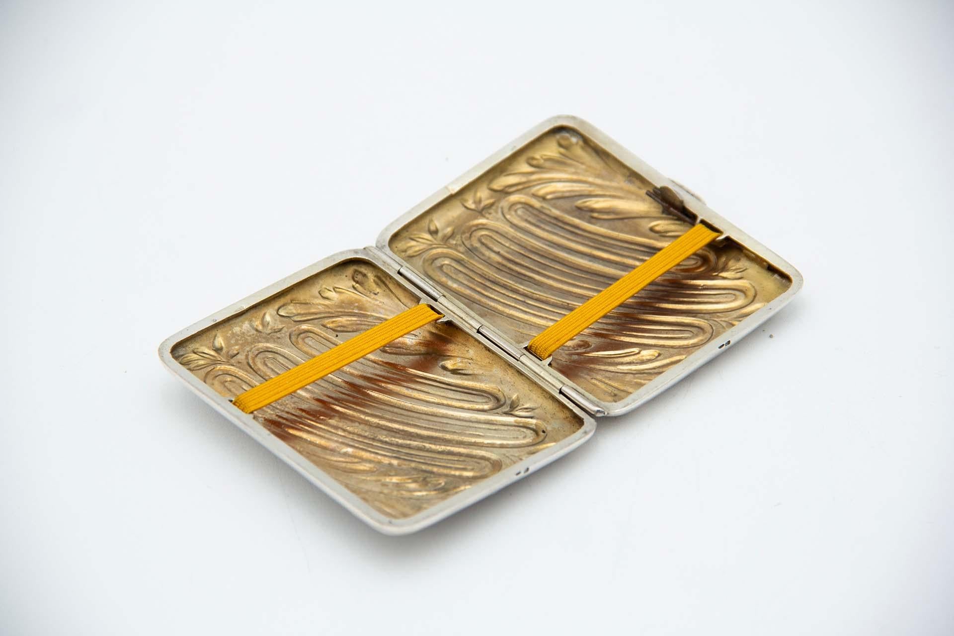 Description: Rectangular silver cigarette case with embossed floral motifs in the Art Nouveau style and gold interior. Metal: Silver. Origin: Portuguese. Brand: javali II Title. Weight: 49.34 grams. Dimensions: 8cmx1.3cm. Content: 833/1000. Assay