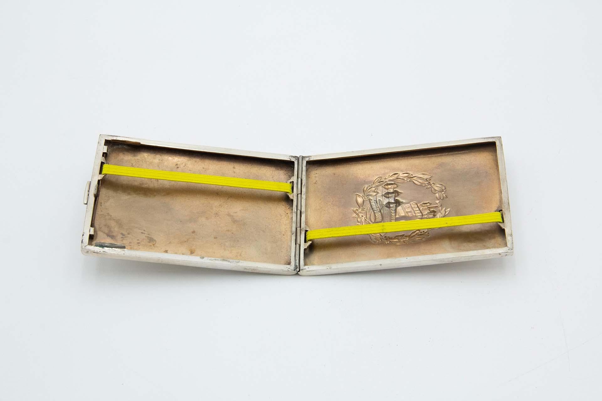 Description: Rectangular silver cigarette case with low reliefs alluding to the Belém Tower and Portugal. Metal: Silver. Origin: Portuguese. Mark: Eagle Head. Weight: 137.53 grams. Dimensions: 11.5cmx1.4cm. Content: 833/1000. Assay Mark: Yes,