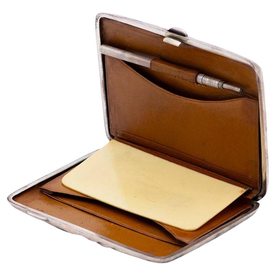 Description: Rectangular silver wallet/diary, guilloche bands at the top, leather interior and mechanical pencil. Metal: Silver. Origin: English. Brand: Birmingham. Weight: 123.55 grams. Dimensions: 10.3cmx1.5cm. Content: 925/1000. Assay Mark: Yes,