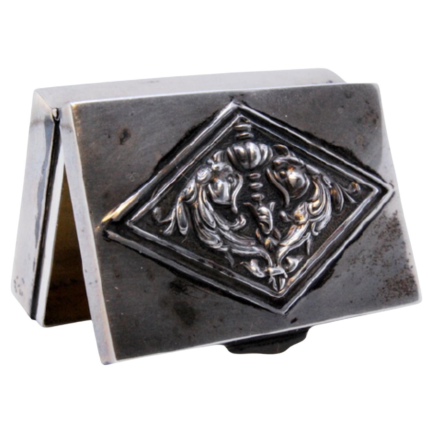 Rectangular silver pill box with raised applications on the hinged lid