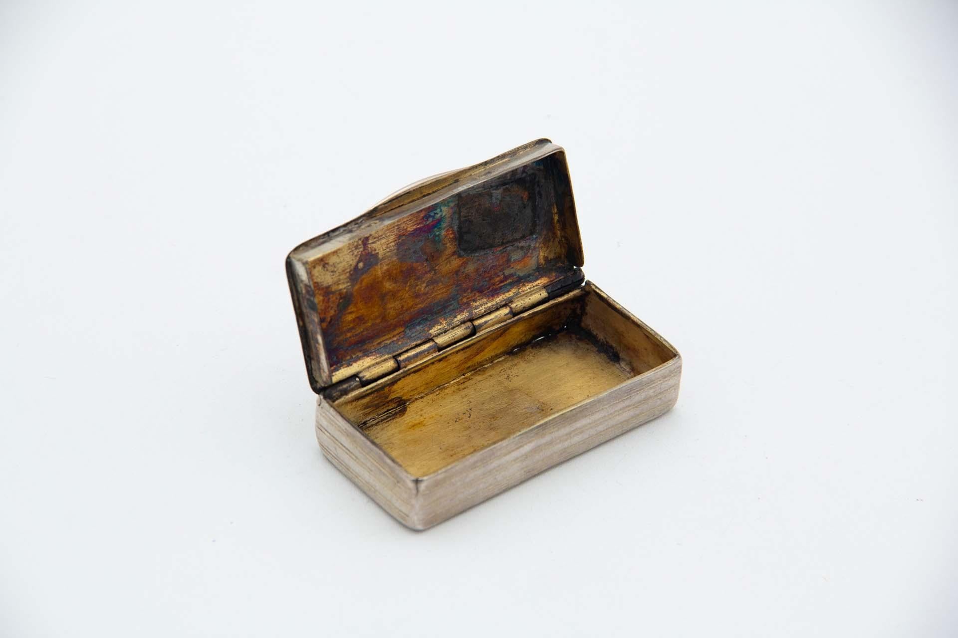 Beschreibung: Rechteckige silberne Schnupftabakdose mit Rillen und Kränzen auf dem Scharnierdeckel eingraviert. Metall: Silber. Herkunft: Portugiesisch. Marke: Porto Coroa. Gewicht: 59,01 Gramm. Abmessungen: 7cmx1,6cm. Inhalt: 833/1000. Prüfzeichen: