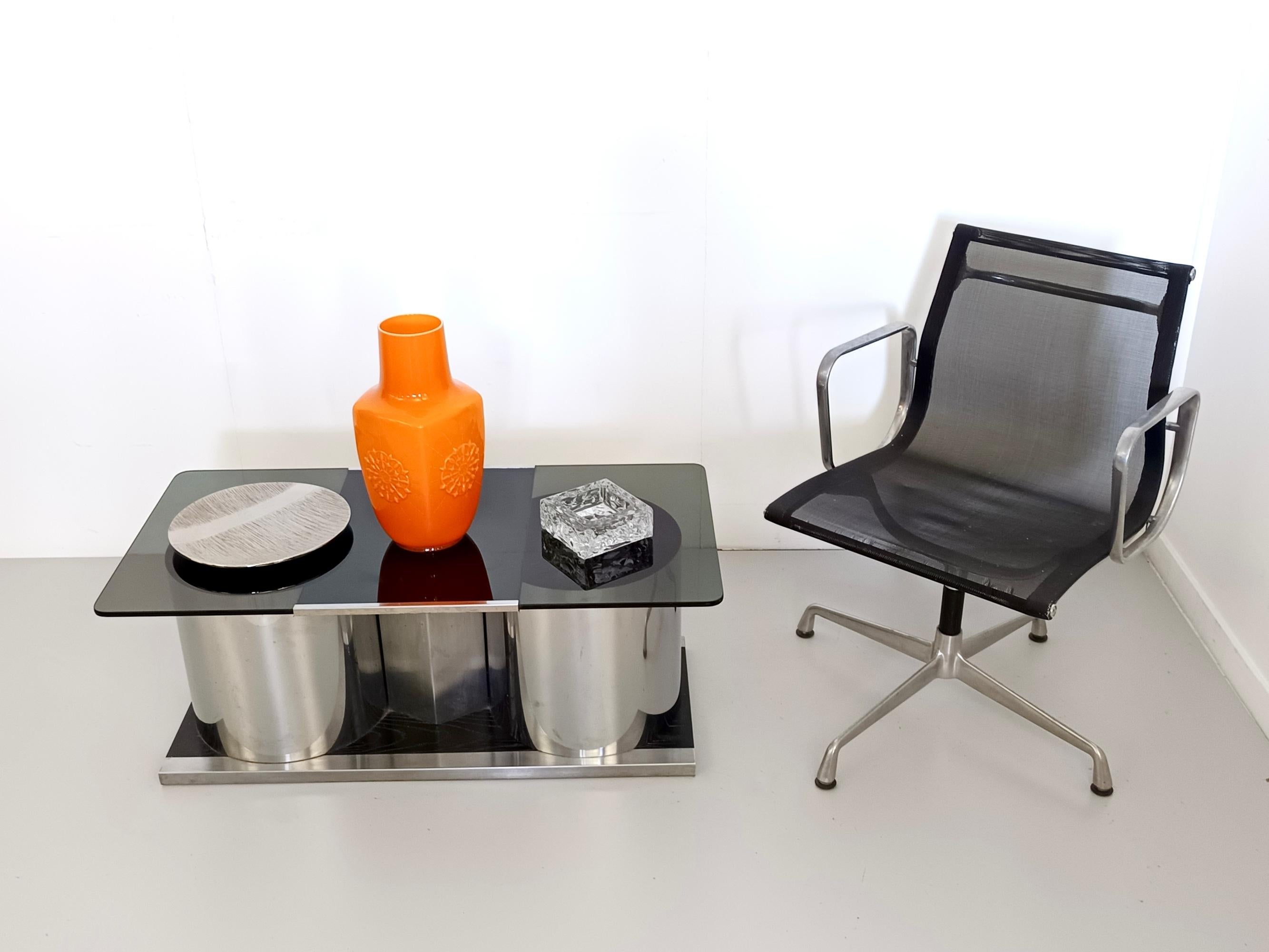 Made in Italy, 1970s.
This is an elegant coffee table or bar with a high-quality rectangular tempered smoked glass top that swivels to reveal two steel cylinders with a lacquered plastic interior. The base is set on a lacquered beech platform.
It is