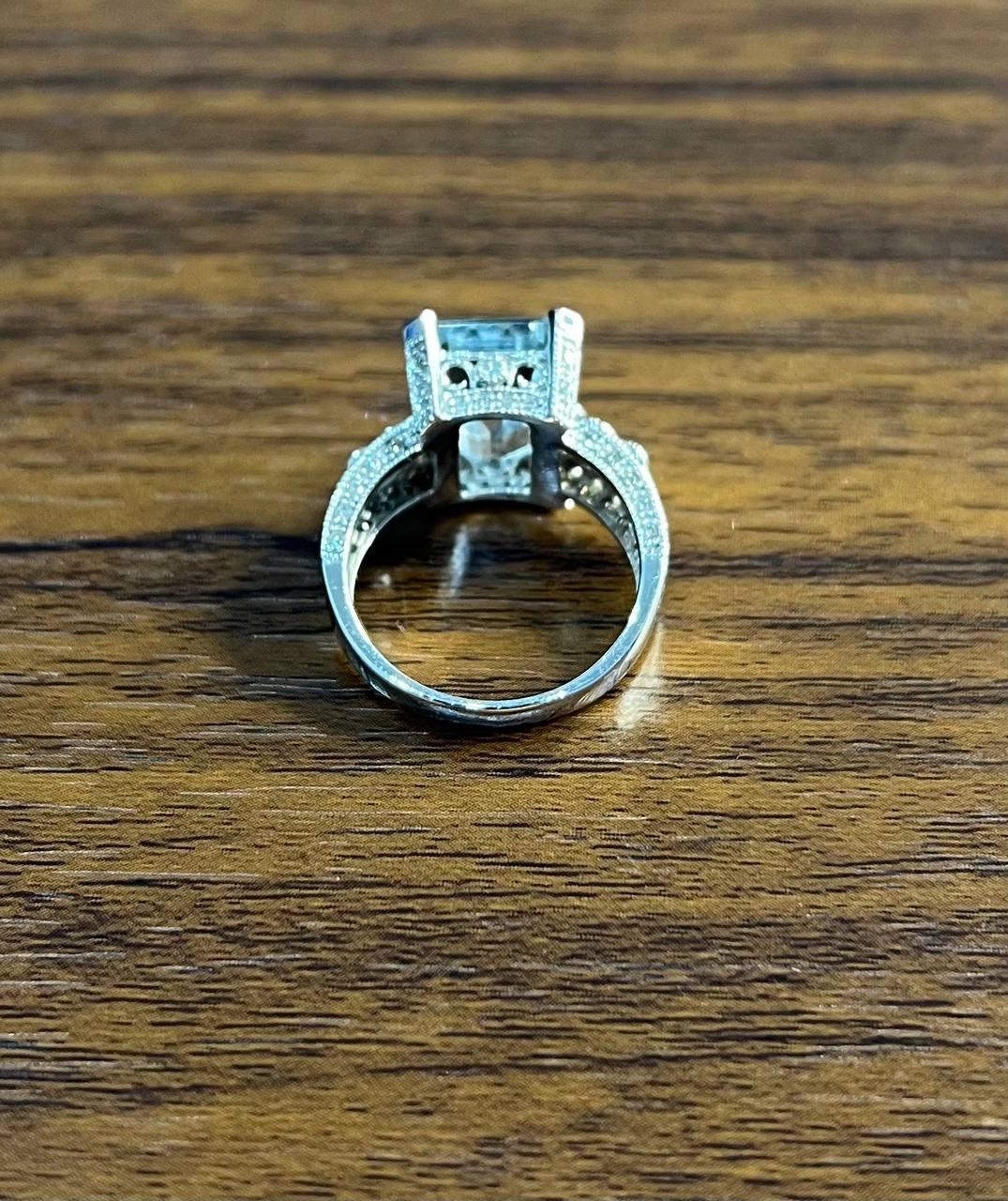 A sophisticated band ring featuring a striking blue emerald-cut topaz.

The ring is adorned with white diamonds, enhancing the central stone's brilliance. Crafted in 14K White Gold this exquisite piece is both elegant and timeless.