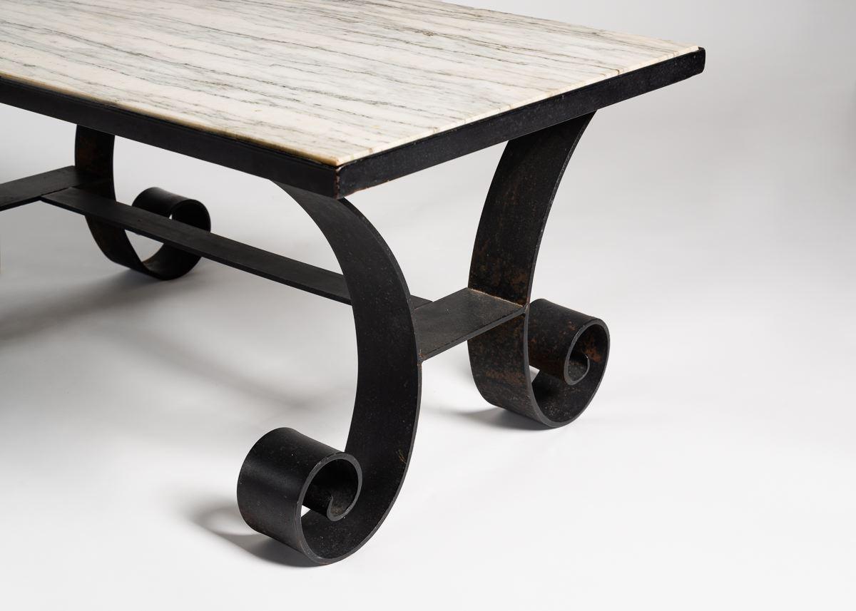 A playful, wrought iron table with a white, rectangular stone top.