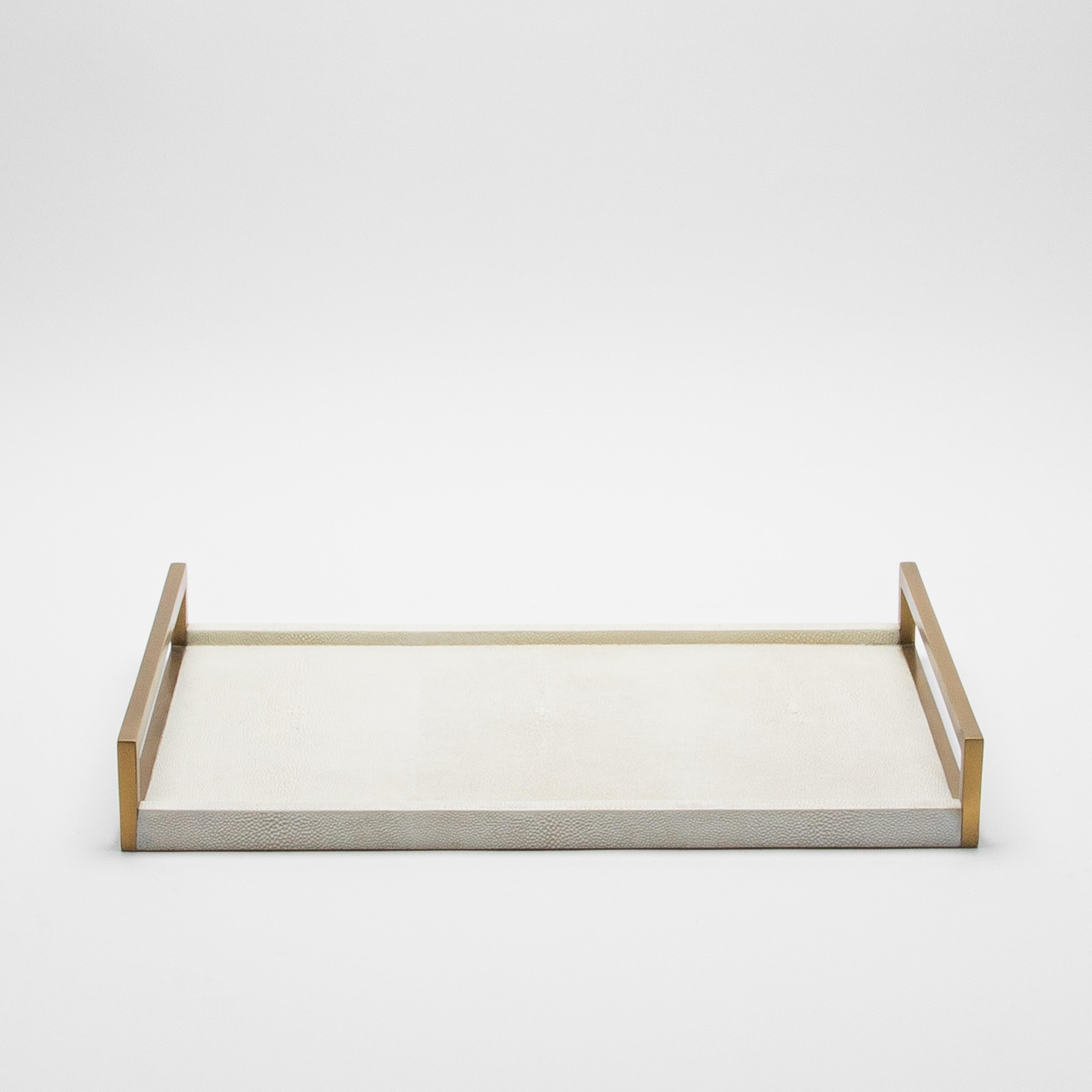 This elegant rectangular tray by R&Y Augousti is a stunning display of luxurious craftsmanship. With its sleek natural cream shagreen surface, it exudes sophistication, while the contrasting bronze patina brass handles add a touch of opulence. Every