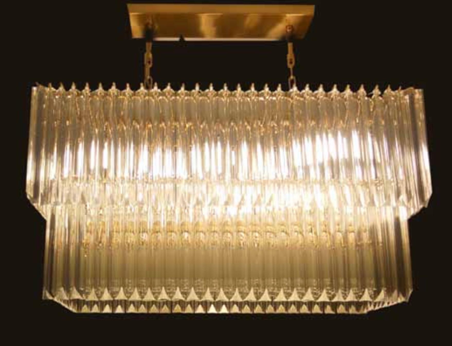 Italian rectangular chandelier with clear Murano glasses cut in Triedri technique arranged in two layers on gold finish metal frame / Inspired by Venini / made in Italy
10 lights / E26 or E27 type / max 60W each
Measures: width 35.5 inches, depth 14
