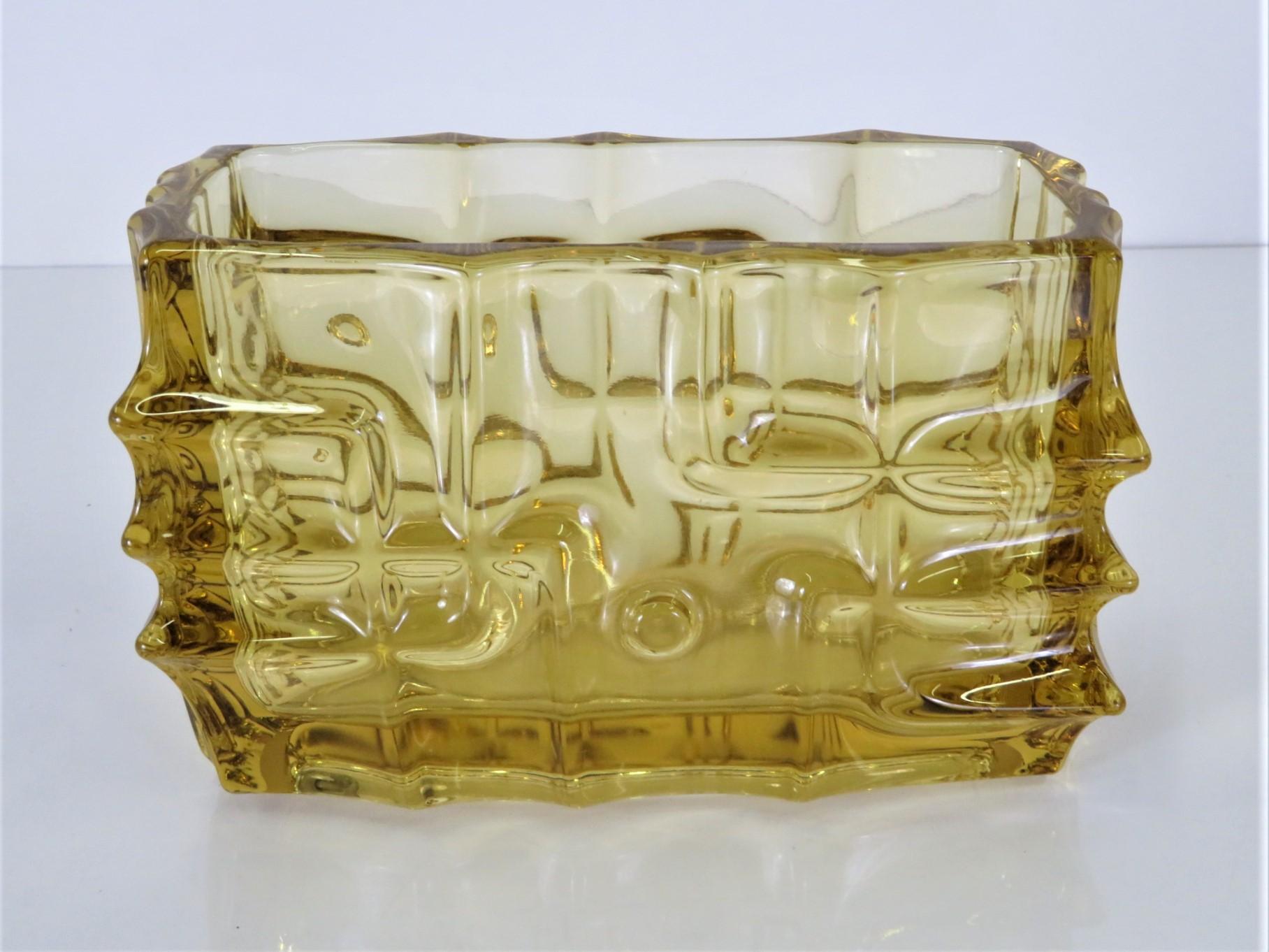 Vladislav Urban, né en 1937 à Pilsen, en Tchécoslovaquie, est un créateur de verre et de bijoux. Urban, entre autres, a joué un rôle déterminant dans l'évolution de la production tchèque de verre pressé. Ce vase en verre pressé ambre, datant de