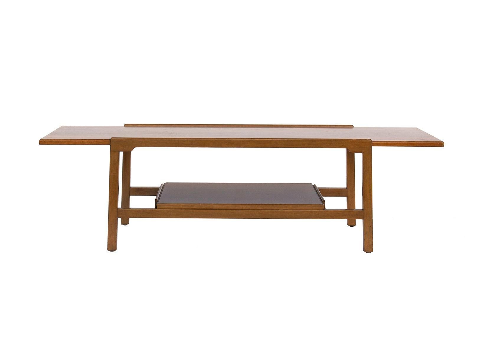 USA, 1950s
Walnut coffee table signed with Dunbar label. The top is in a faux walnut laminate, the frame in walnut. It has a shelf below the top surface, great for storing or display of magazines, books, or objects.
CONDITION NOTES: One leg is