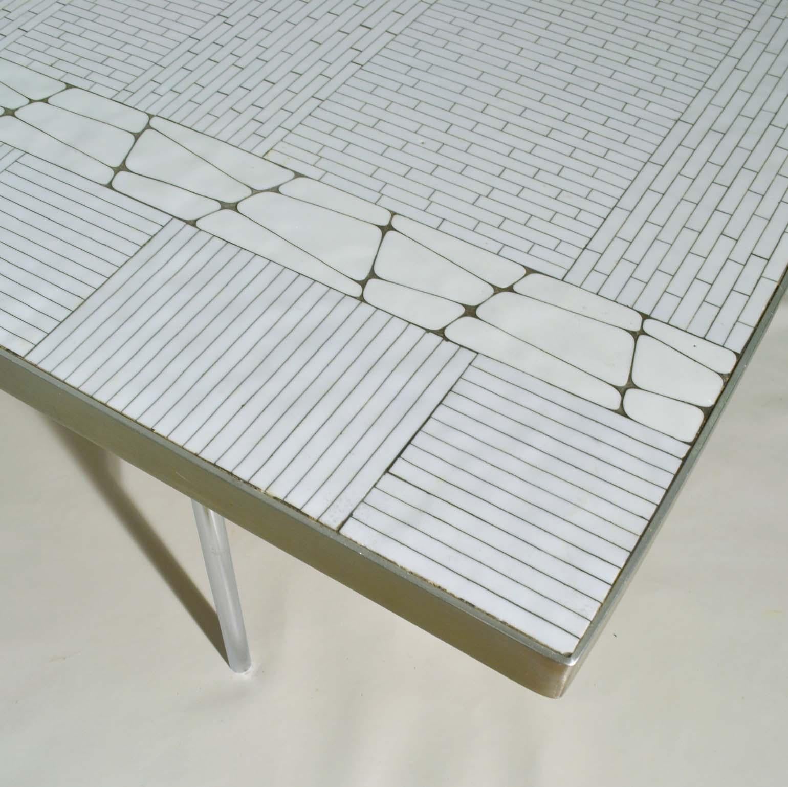 La table basse rectangulaire en mosaïque blanche est composée de centaines de carrés et de rectangles en verre pour former un motif abstrait, populaire dans les années 1950-1970. Les bords de la table sont enveloppés d'aluminium poli. La table