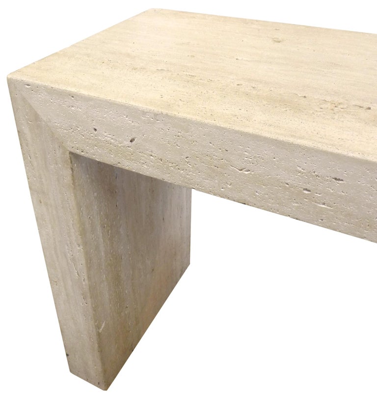 An elegant, wonderfully minimal travertine console table. A powerful, simple yet substantial form of raw, unpolished travertine with pitted surface and classic variegated oatmeal hue. An exceptional utilitarian furnishing in a much admired natural
