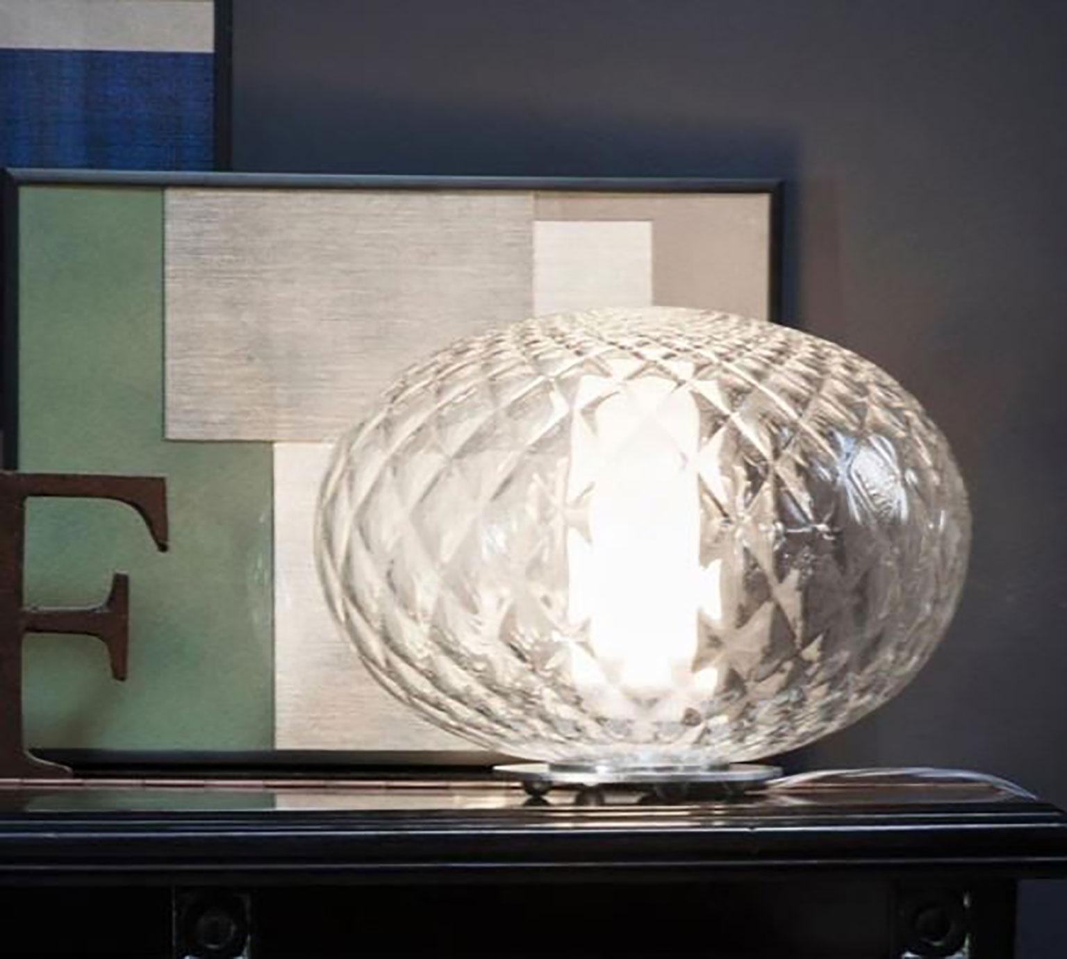 The Recuerdo table lamp designed by Mariana Pellegrino Soto for Oluce. An elegant crystal matelassé or quilted effect creates a refined, classic luminescence from this timeless lamp. An LED light source is protected by an internal frosted glass