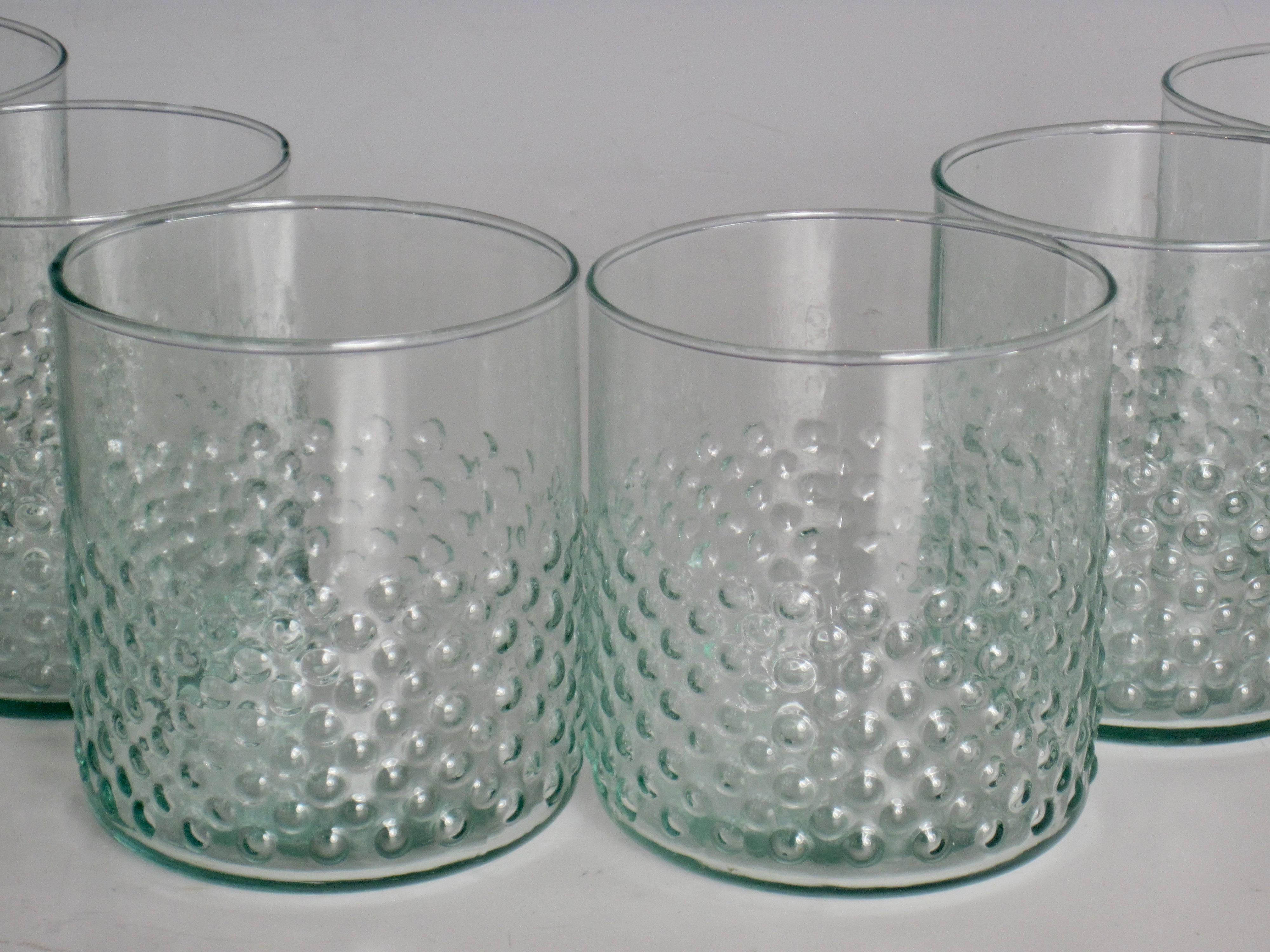 Set aus sechs gepunkteten Lowball-Gläsern aus recyceltem Glas mit klarer grüner Tönung. Das gepunktete Muster befindet sich auf der äußeren unteren Hälfte des Glases und liegt gut in der Hand.
Aufgrund der Natur von recyceltem Glas können