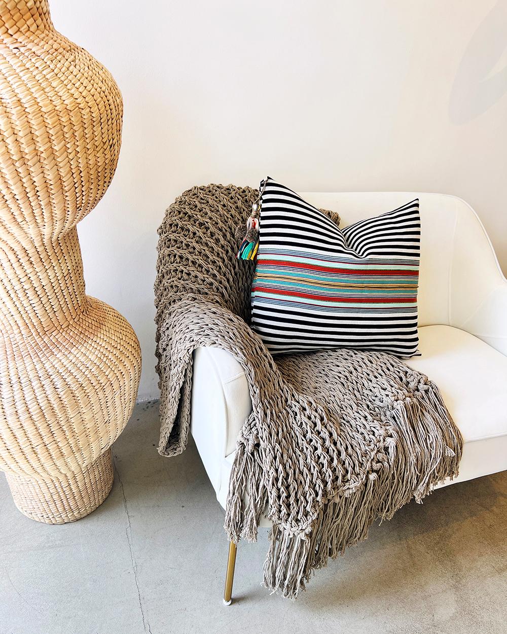 This gray artisan throw is handmade from recycled cotton, a natural material that gives it a high-end look and feel. With an open weave design, it adds a luxurious element to home decor. This designer piece in classic black is perfect to bring a