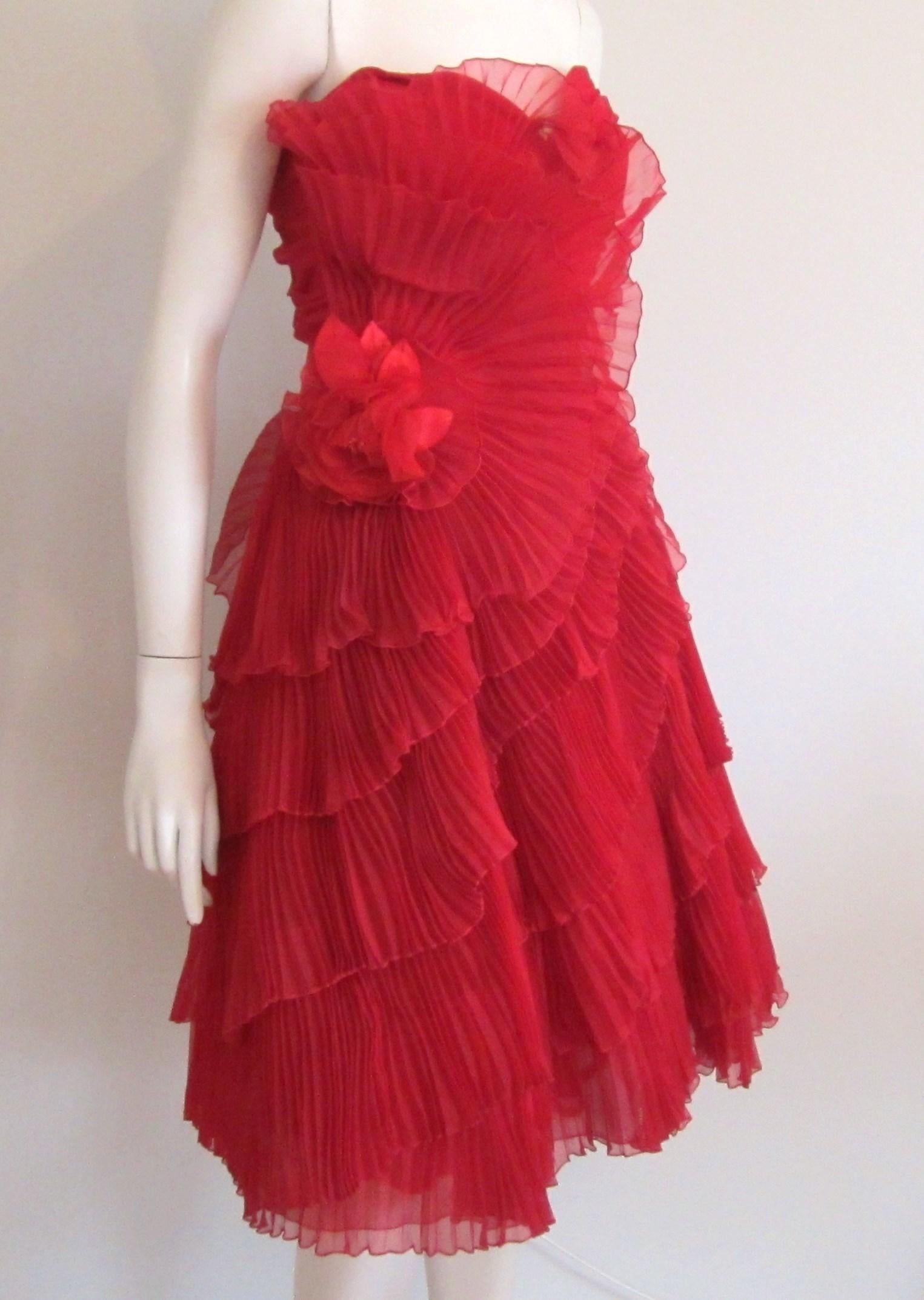 Red Hot Strapless Accordion Pleated 1950s Strapless Dress. Sweet Heart bodice. Layers and Layers of accordion pleating! Large floral adornment. Side zipper and clip closure. Belt closure on the side. Boned Bodice. Tulle underskirt as well as a lace