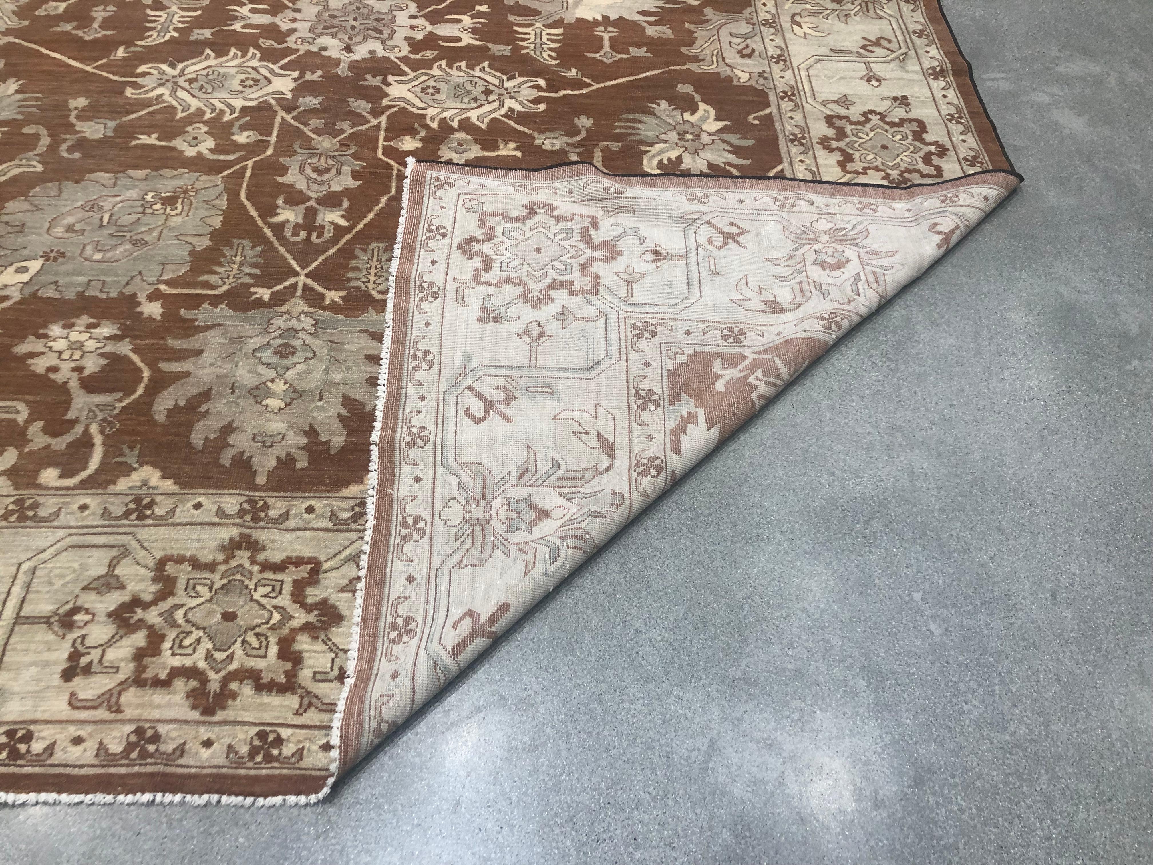 A red core with stylized floral motif stands at the centre of this traditional Pakistani wool area rug. The contrasting beige border shapes and defines the space. Hand knotted wool.