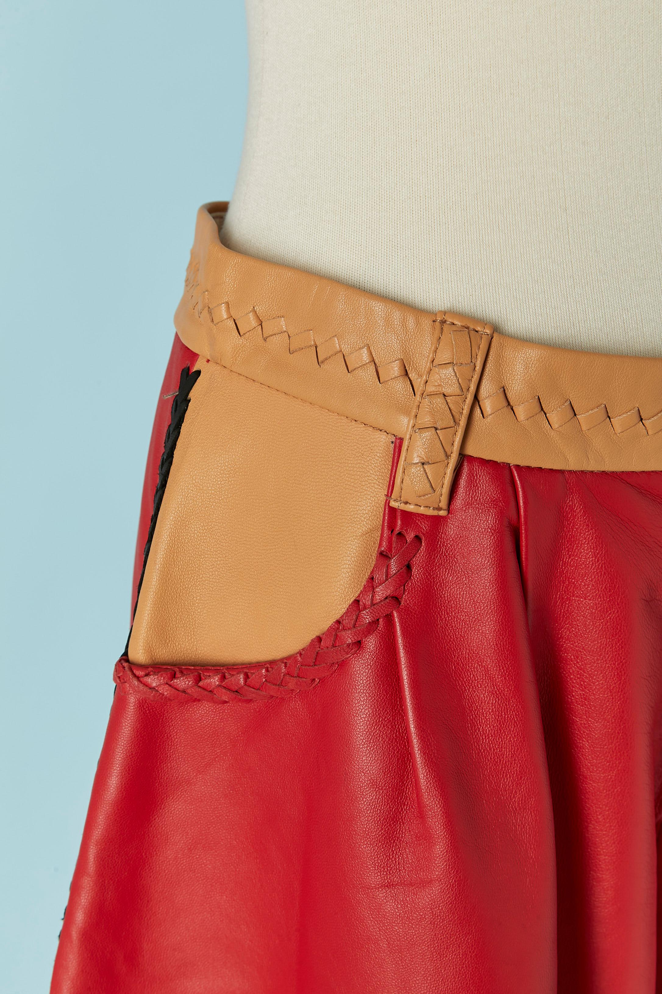 Pantaloncino in pelle rossa e beige con treccia sul bordo. Fodera in cupro. Chiusura con gancio e zip  sulla parte anteriore centrale superiore. Tasca su entrambi i lati. Cintura ad anello. 
TAGLIA 2 /M 