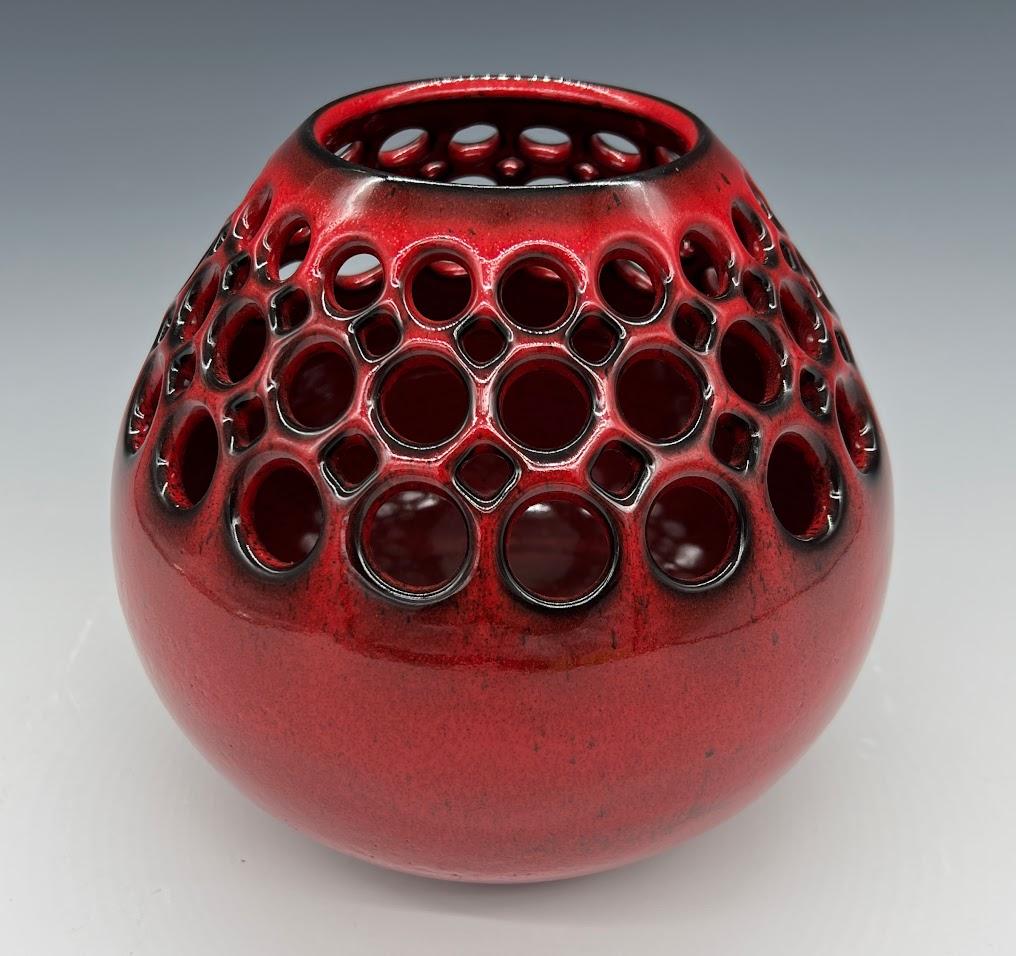 Wheel thrown, hand pierced ceramic tabletop vessel. The vibrant Red Glaze breaks to black along the edges giving it an extra depth and richness. This piece provides the perfect pop of color to any room. It can stand alone as an art piece, or with a